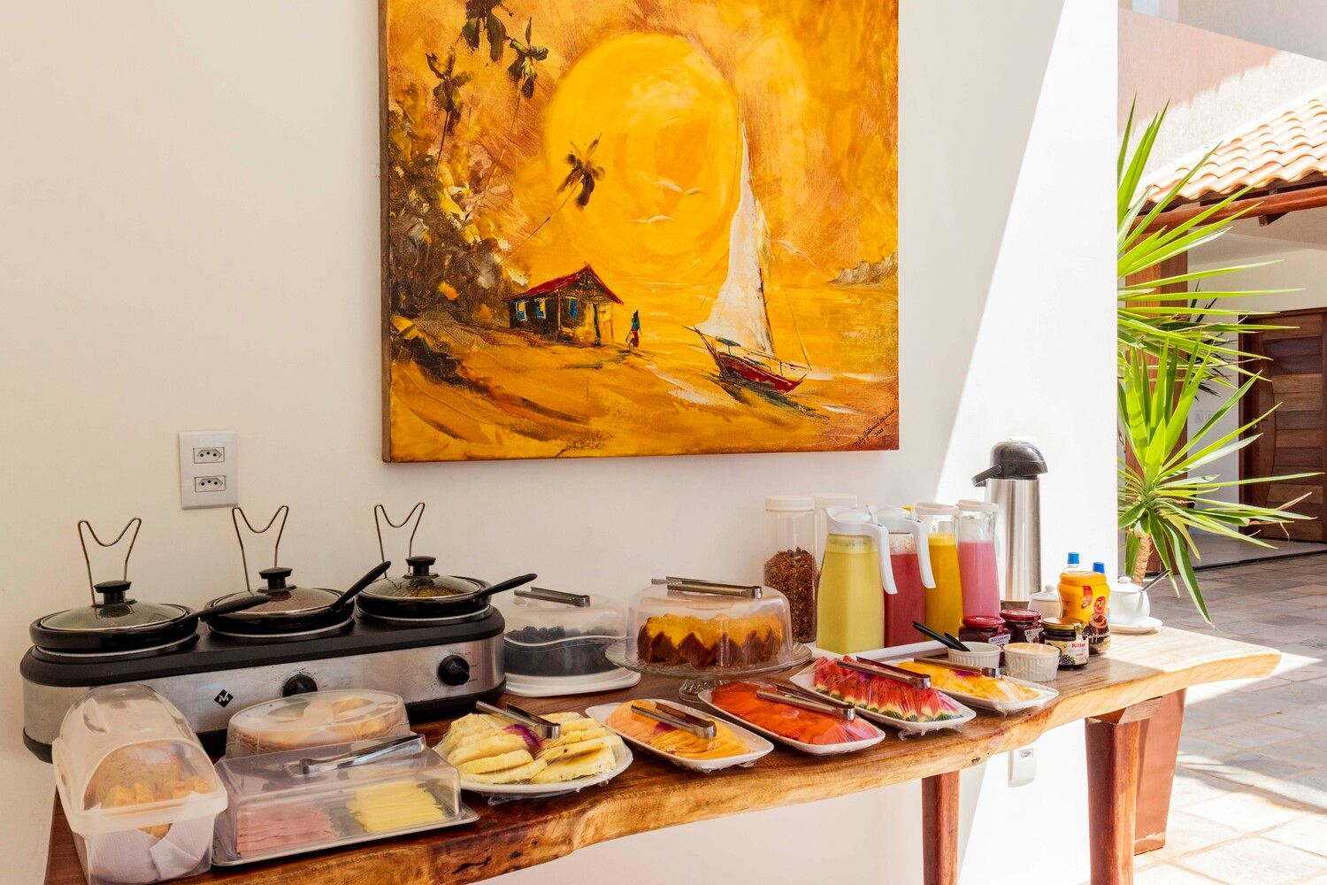 Uma mesa com muita comida e uma pintura na parede.