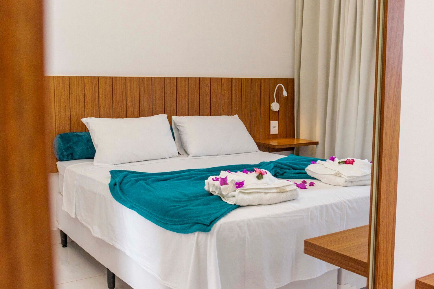 Um quarto de hotel com uma cama grande e um espelho.