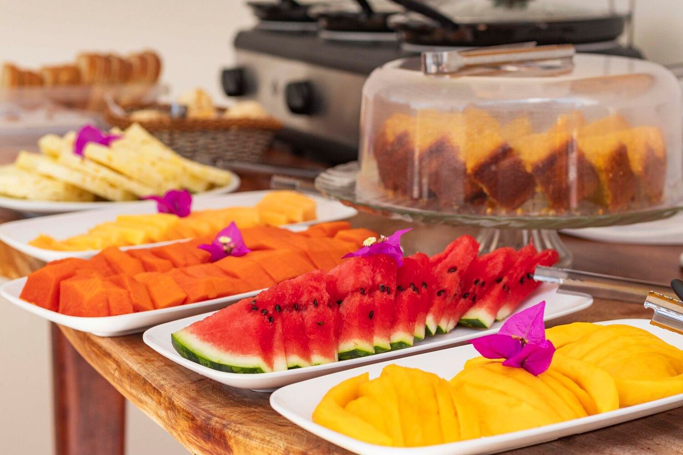 Uma mesa coberta com pratos de frutas e um bolo.