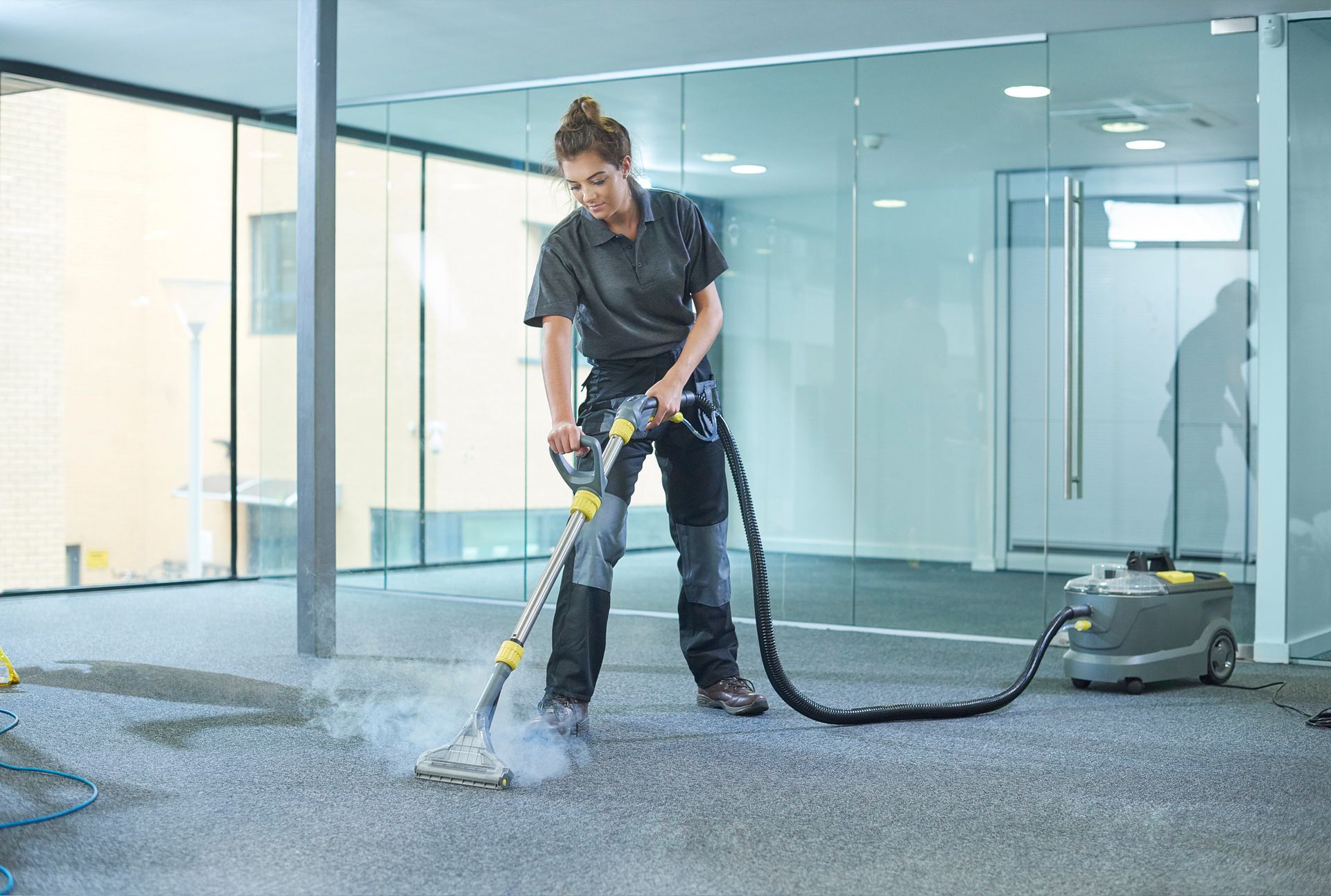 A woman is using a vacuum cleaner to clean a carpet in an office.