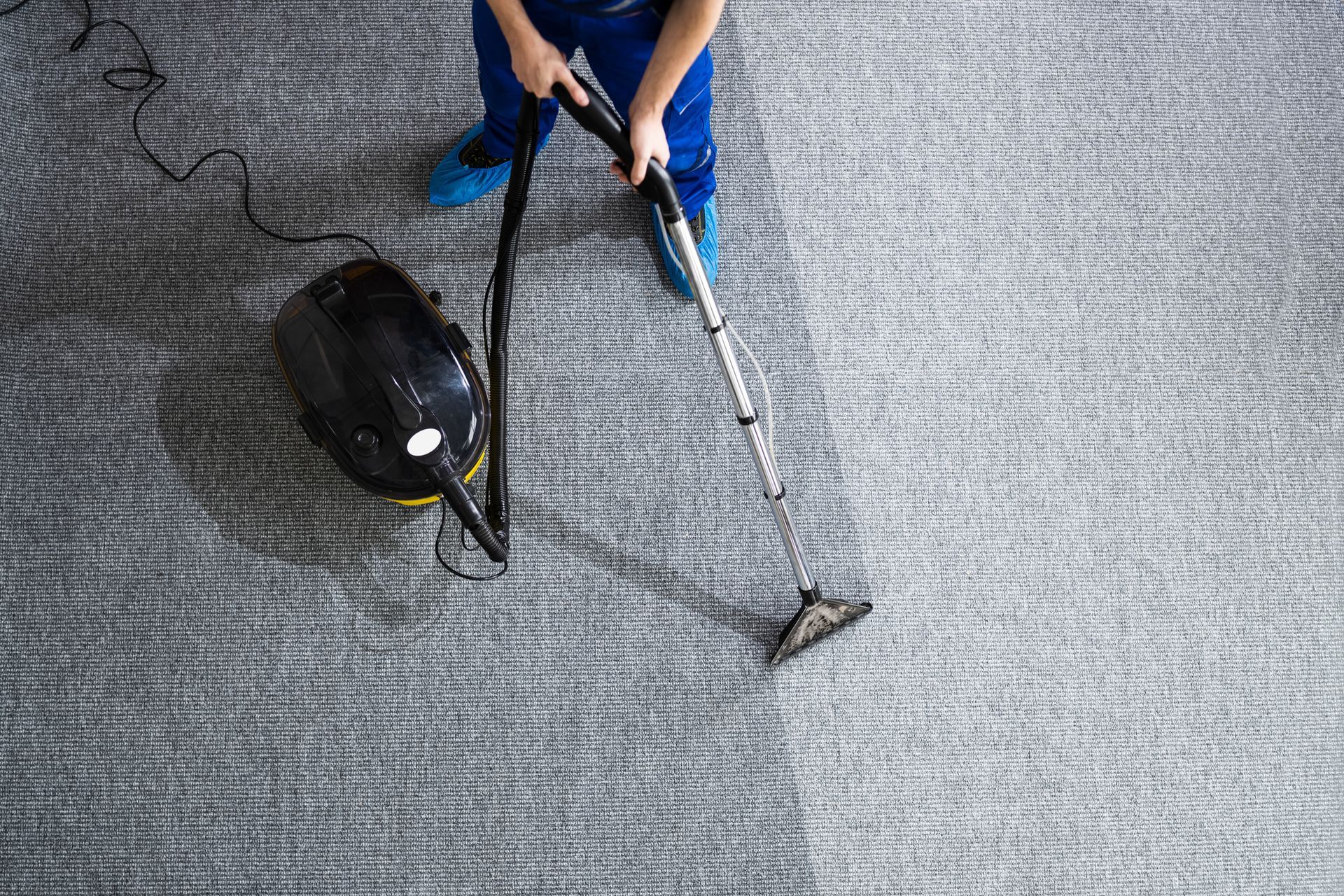 A man is using a vacuum cleaner to clean a carpet.