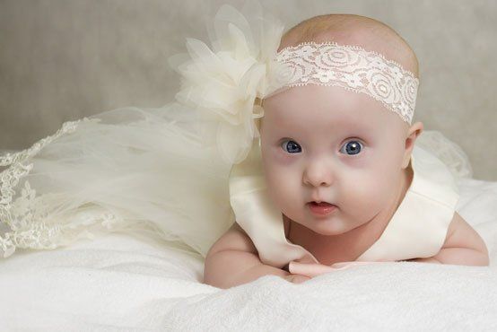 the baby in a dress lies on a pillow