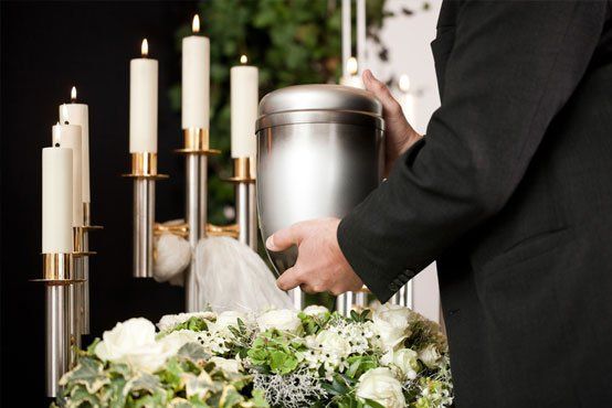 death and dolor - funeral and cemetery, mortician carrying the urn to a bed of white roses