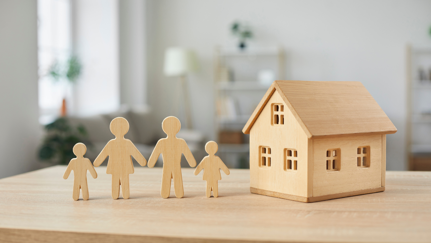 a wooden model of a family standing next to a wooden house on a table .