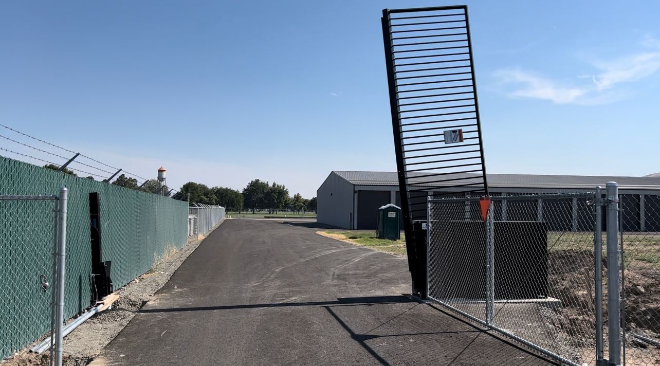 A chain link fence with a gate that is open.