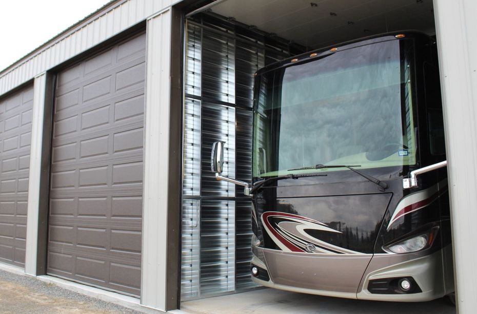 A rv is parked in a garage with the door open.