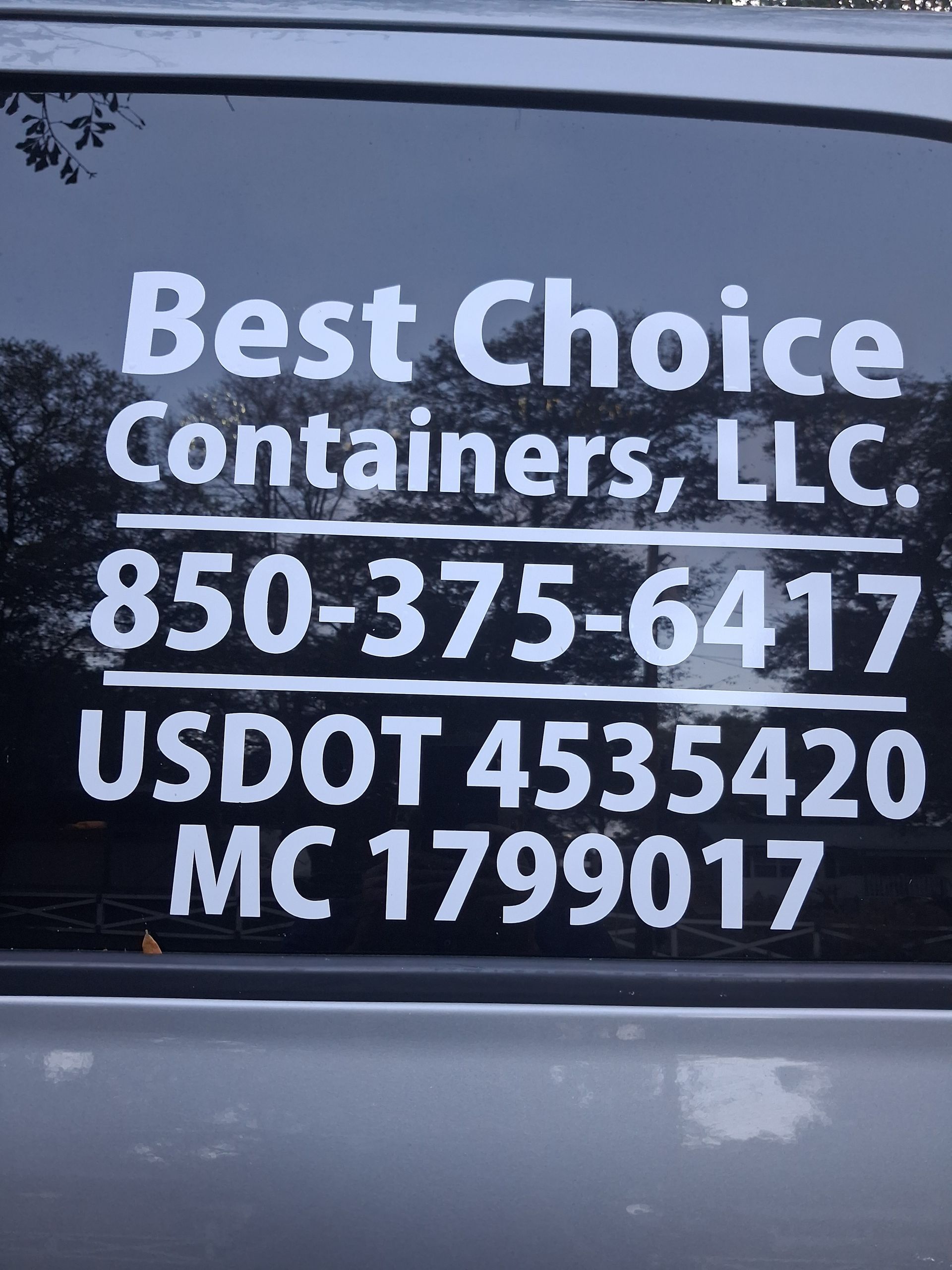 A man is standing in front of a truck with his arms crossed.