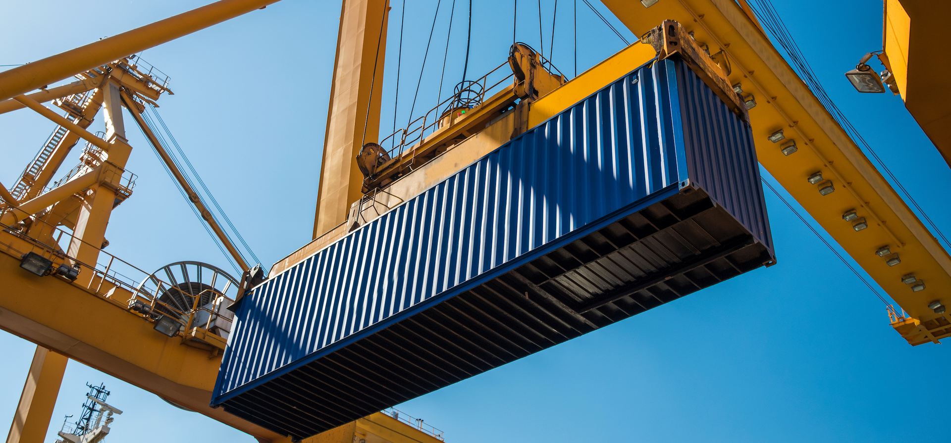 A blue shipping container is being lifted by a crane.