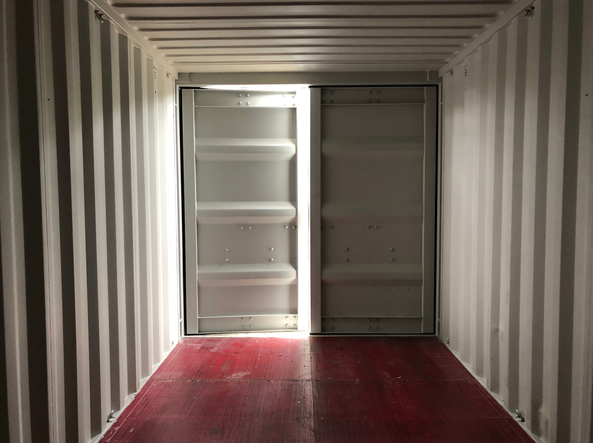 A shipping container with a sliding door and a red floor.