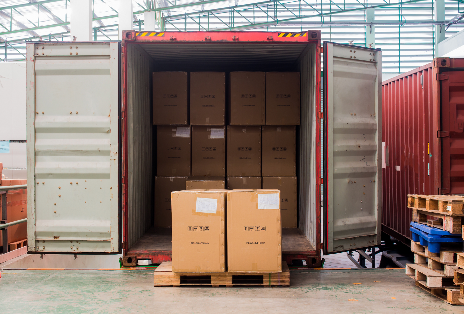 A shipping container filled with boxes and pallets in a warehouse.