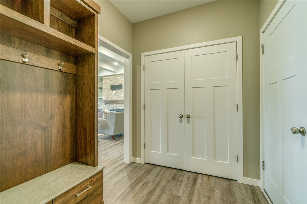 An entryway with a wooden coat rack and bench on the left, white double doors in the center, and a door on the right.
