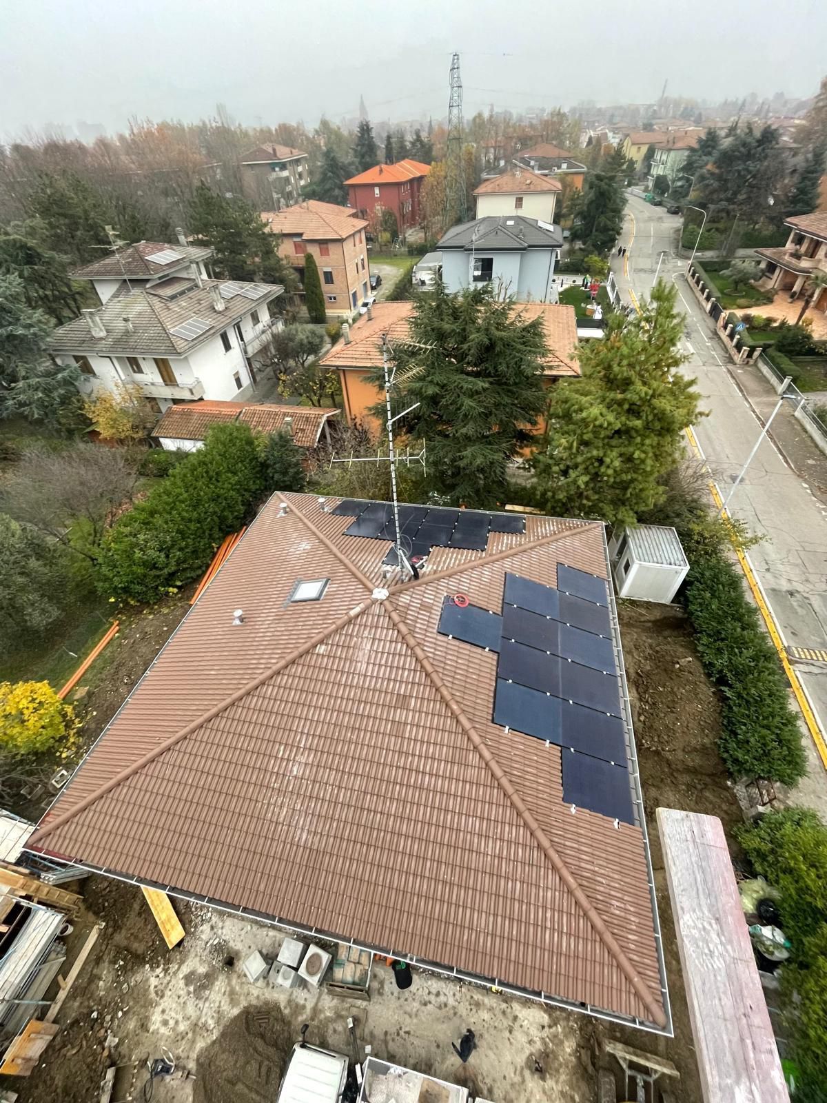 Tetto con pannelli solari installati, con vista su un quartiere suburbano in una giornata nuvolosa.
