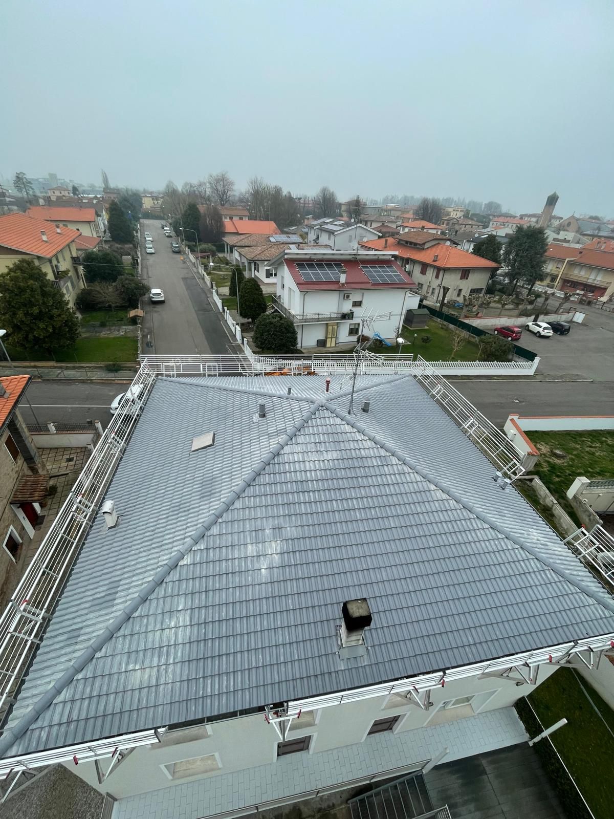 Vista dall'alto di un tetto in ardesia con una città sullo sfondo. Cielo grigio e nuvoloso.