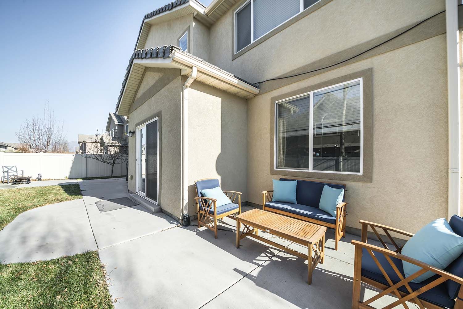 A patio with a couch and chairs in front of a house.