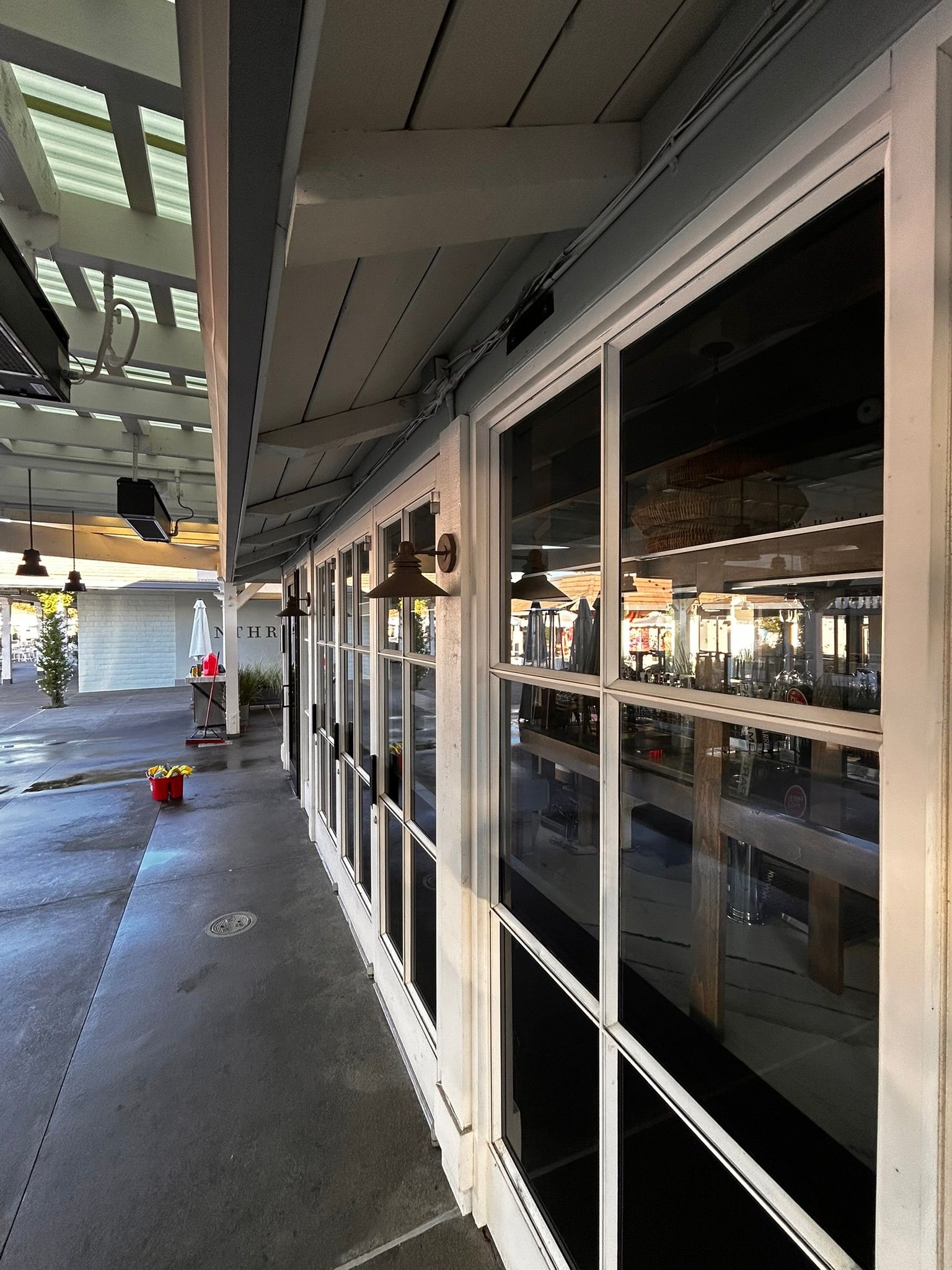 Exterior of a restaurant with a row of windows, white trim, and a patio area.