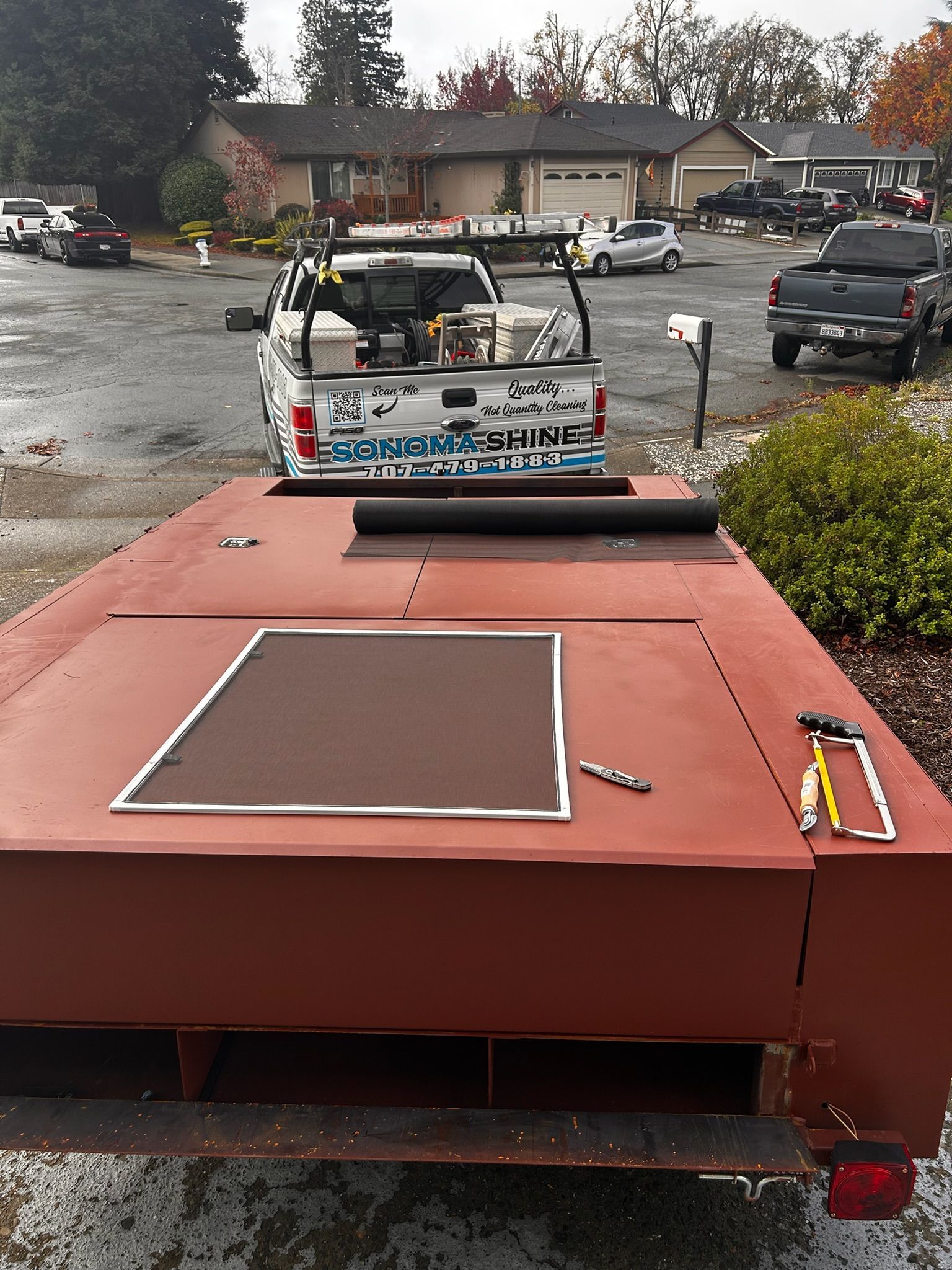 Red trailer bed with a truck behind it in a residential area.