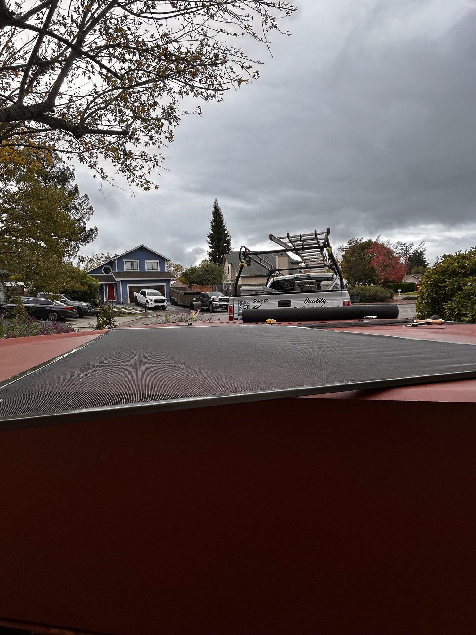 View of a residential street with homes and vehicles under a cloudy sky.