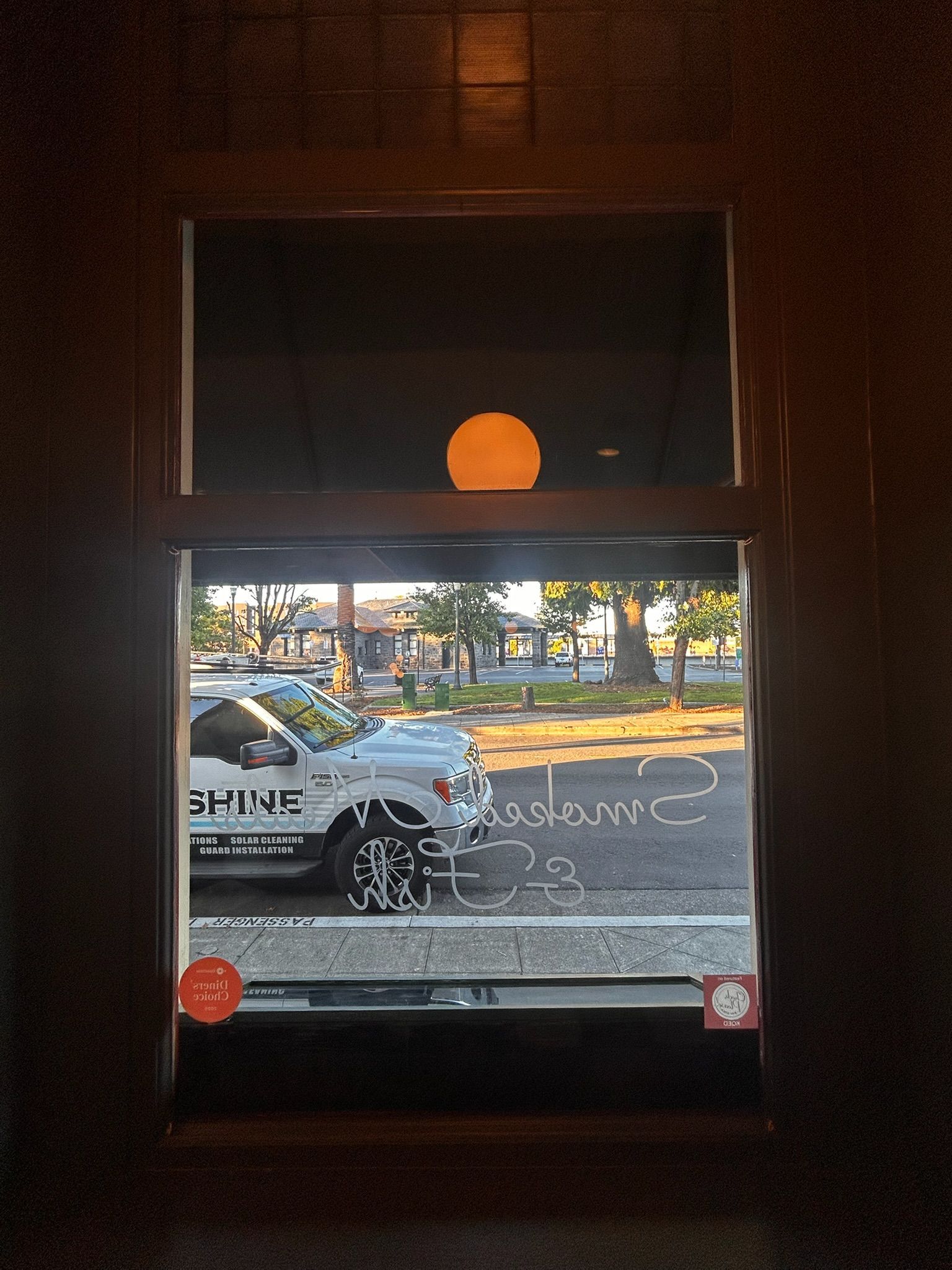 View through a window, showing a police truck parked outside and a round, orange light above.