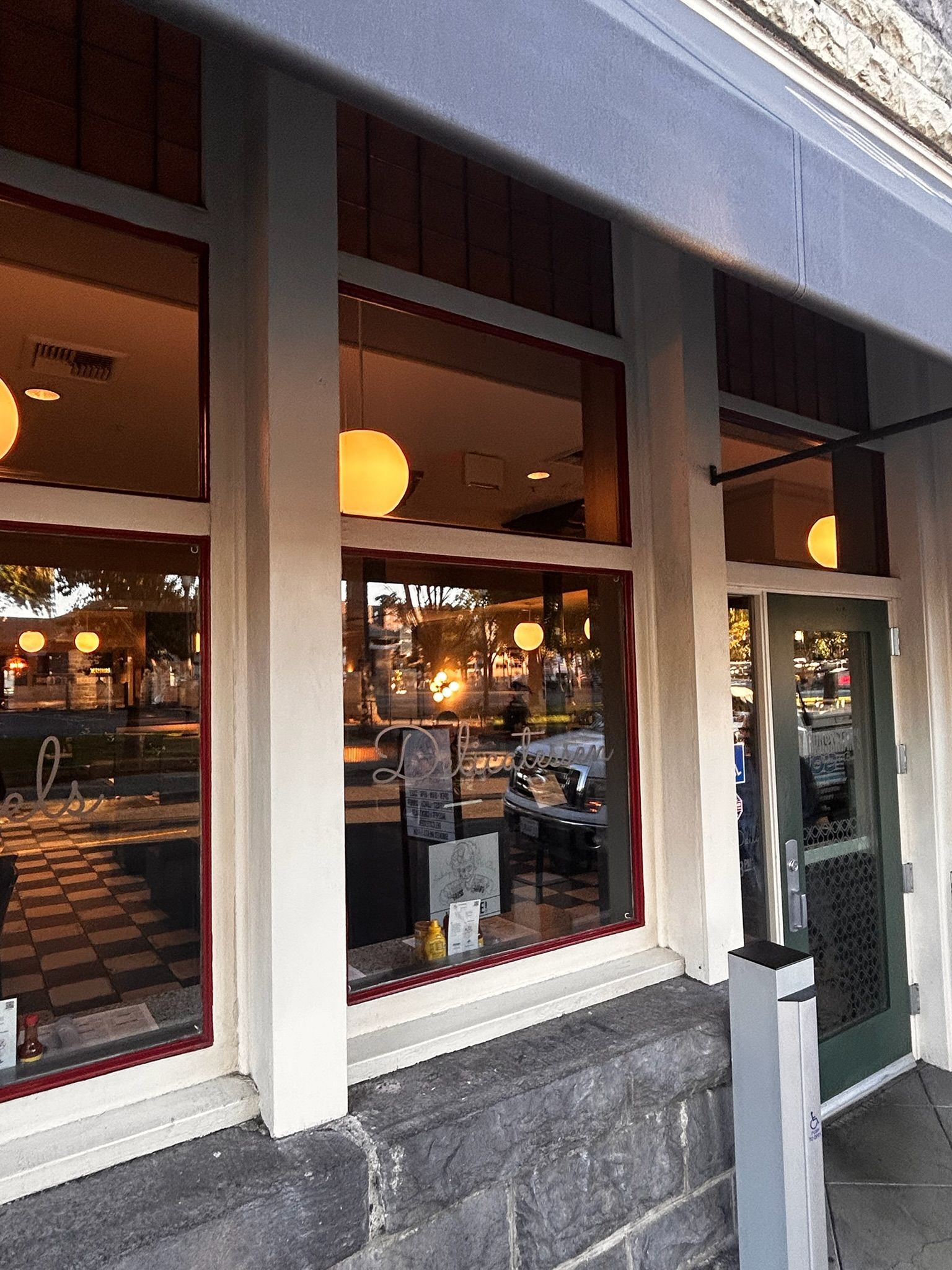 Cafe exterior with large windows, round lights, and visible interior.