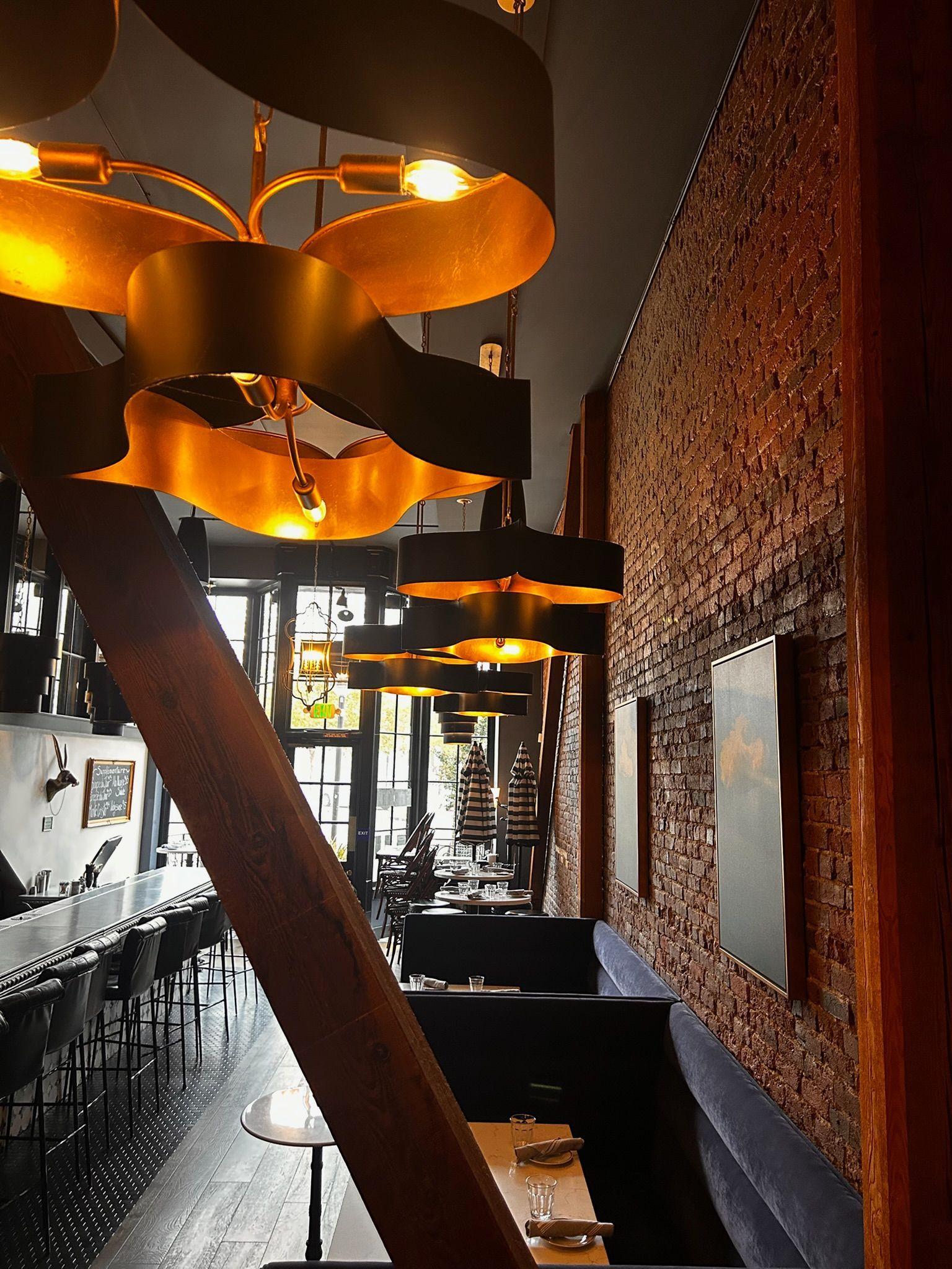 Restaurant interior with curved golden lights and brick wall, tables set for dining.