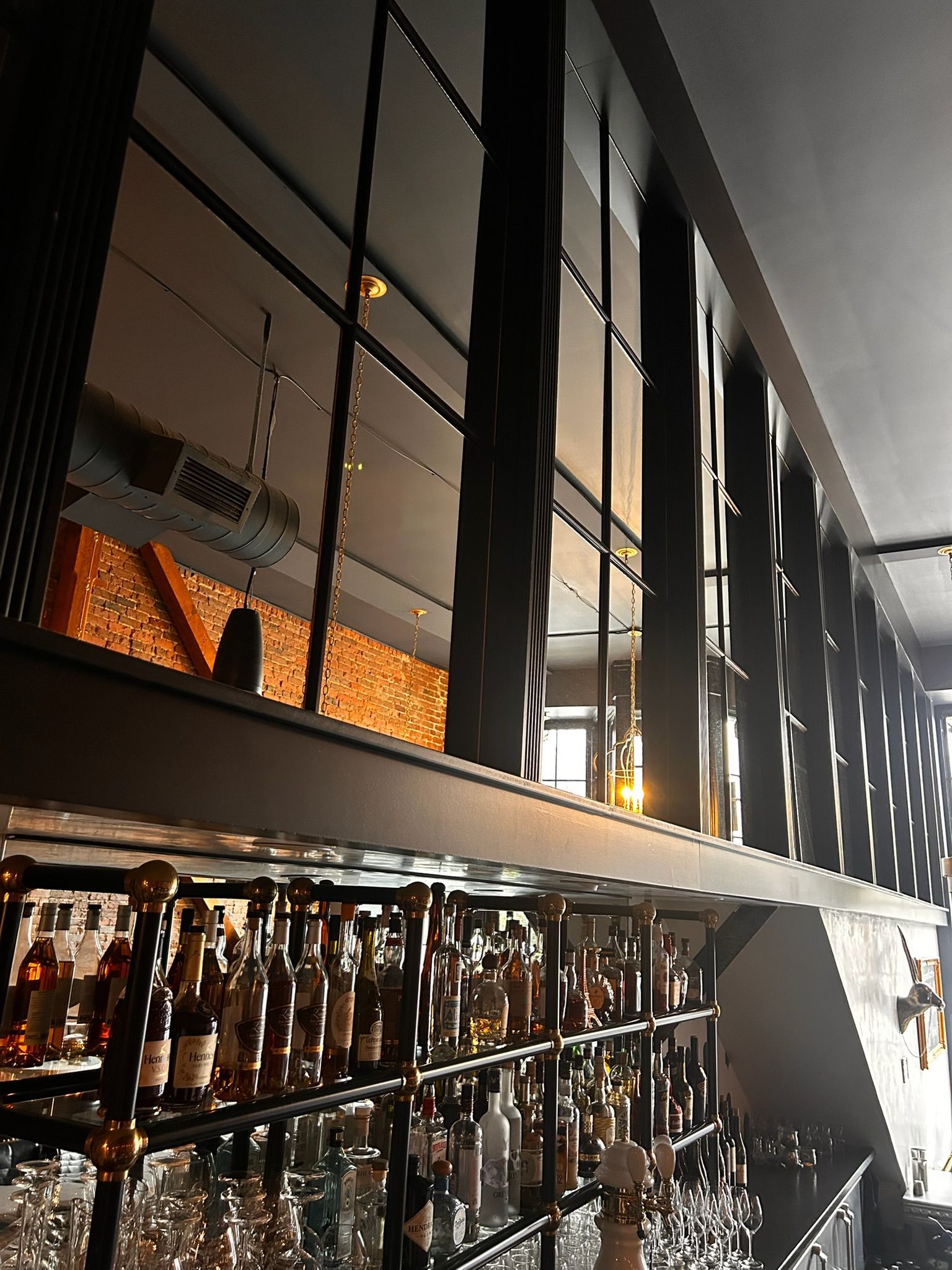 Bar interior with bottles, dark metal beams, and a second level.