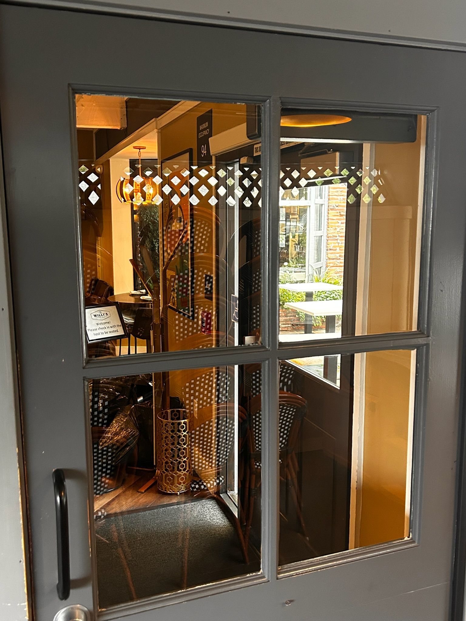 Gray door with a window revealing a warmly lit interior; decorative cutouts on the glass.