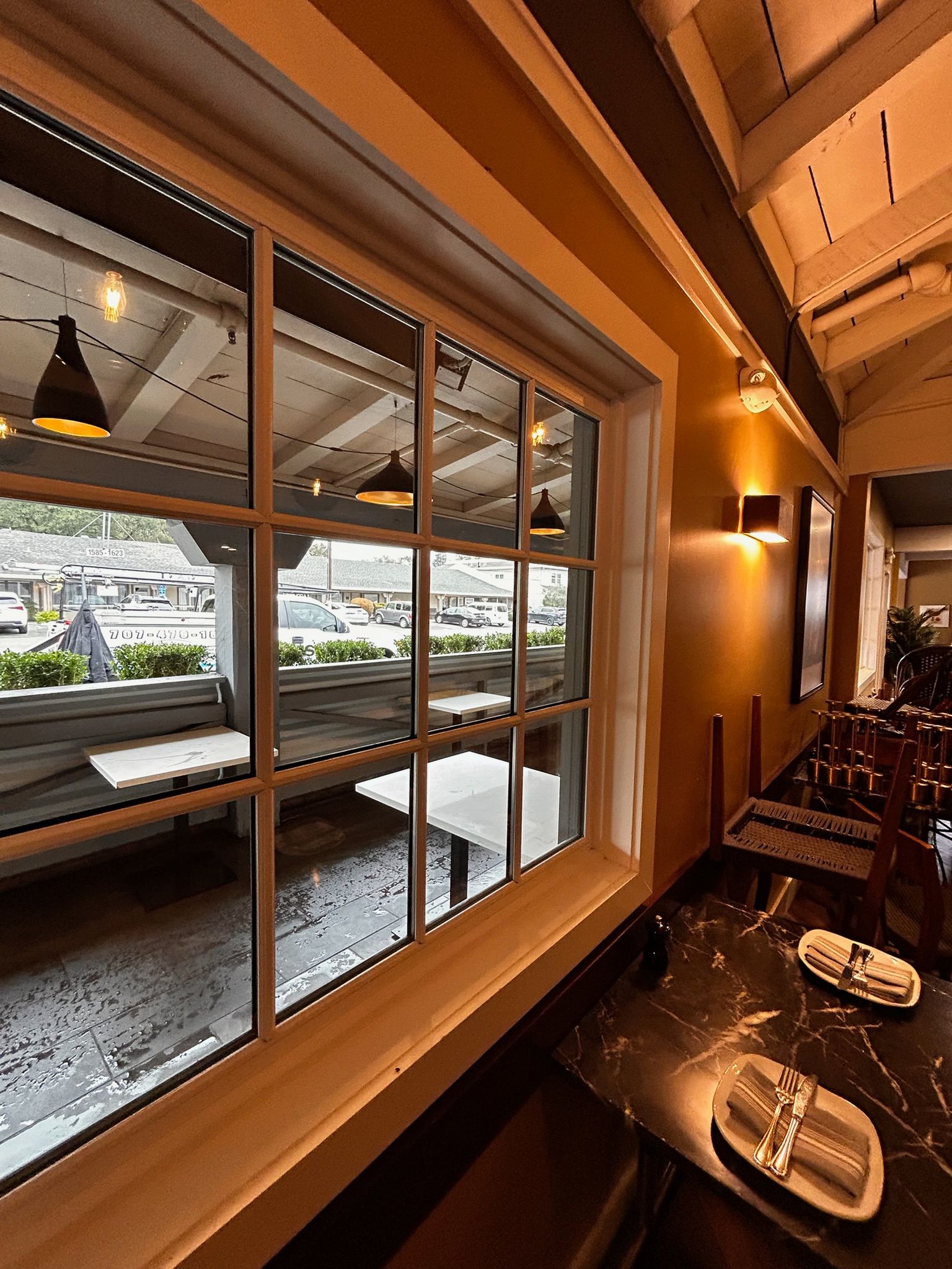 Interior view of a restaurant with a window overlooking an outdoor seating area. 