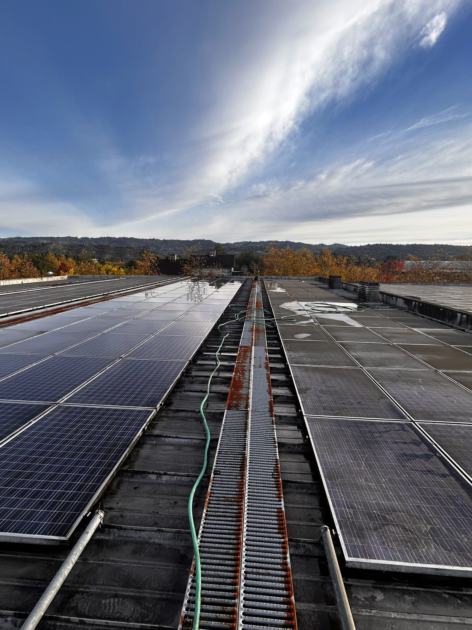 Solar panels on a rooftop under a partly cloudy sky.