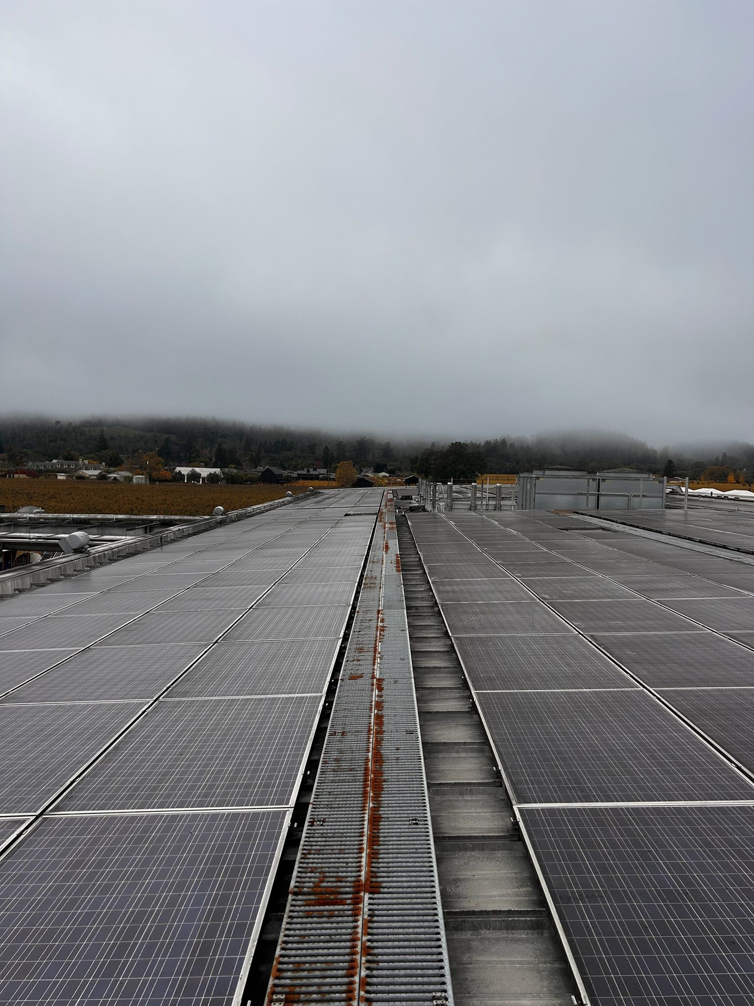 Solar panels on a large rooftop under a cloudy sky.