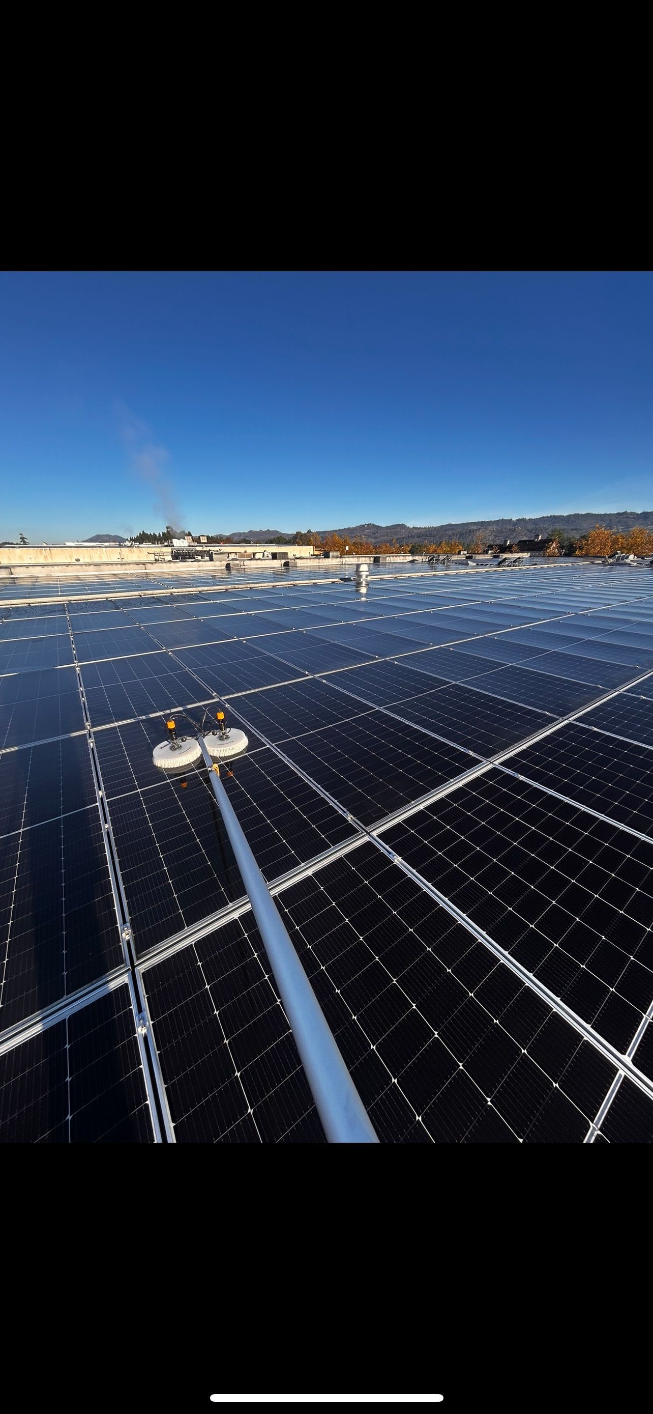 A person cleaning snow from solar panels on a bright, sunny day.