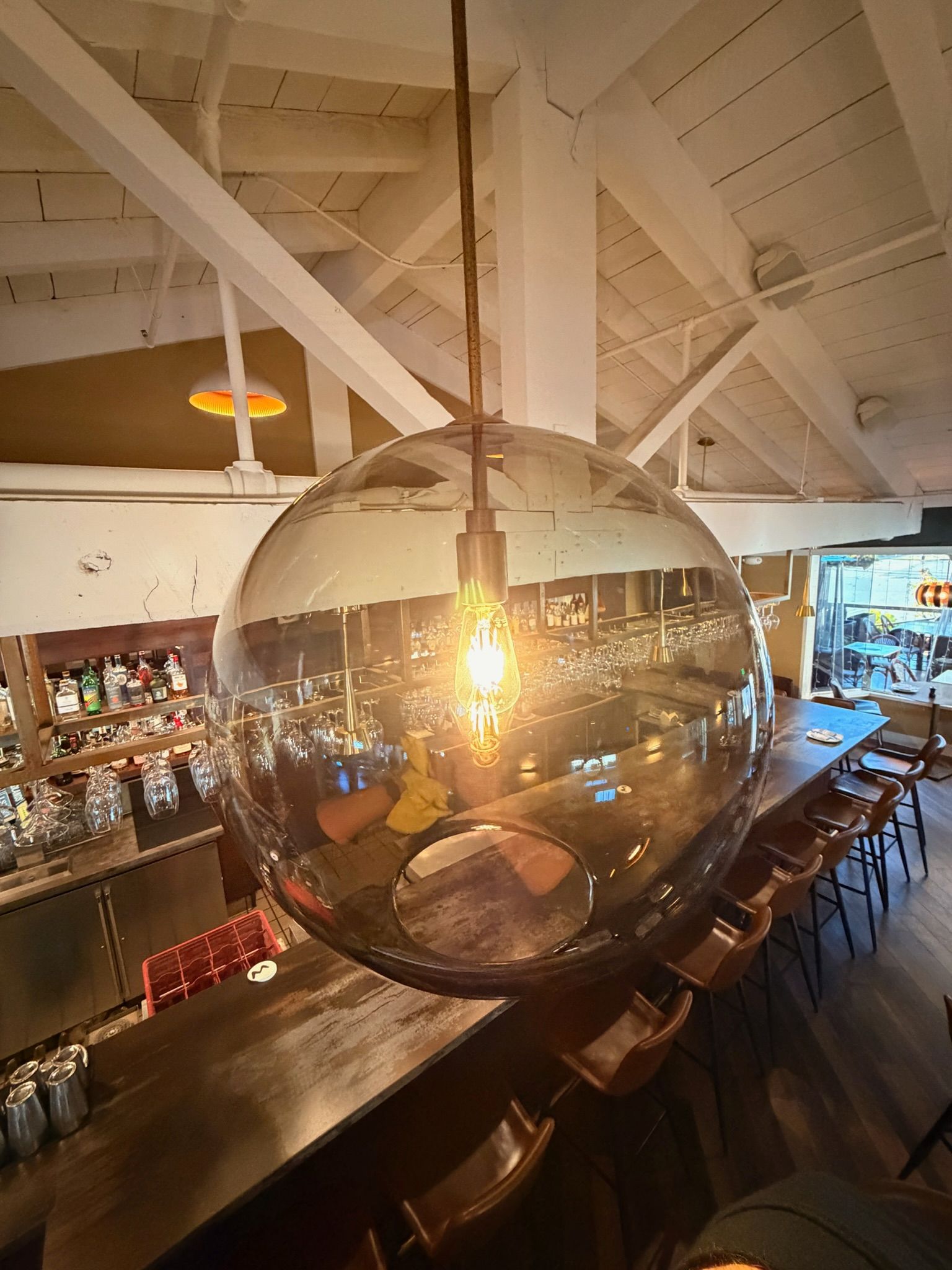 Large, globe-shaped pendant light fixture hanging above a bar with patrons.