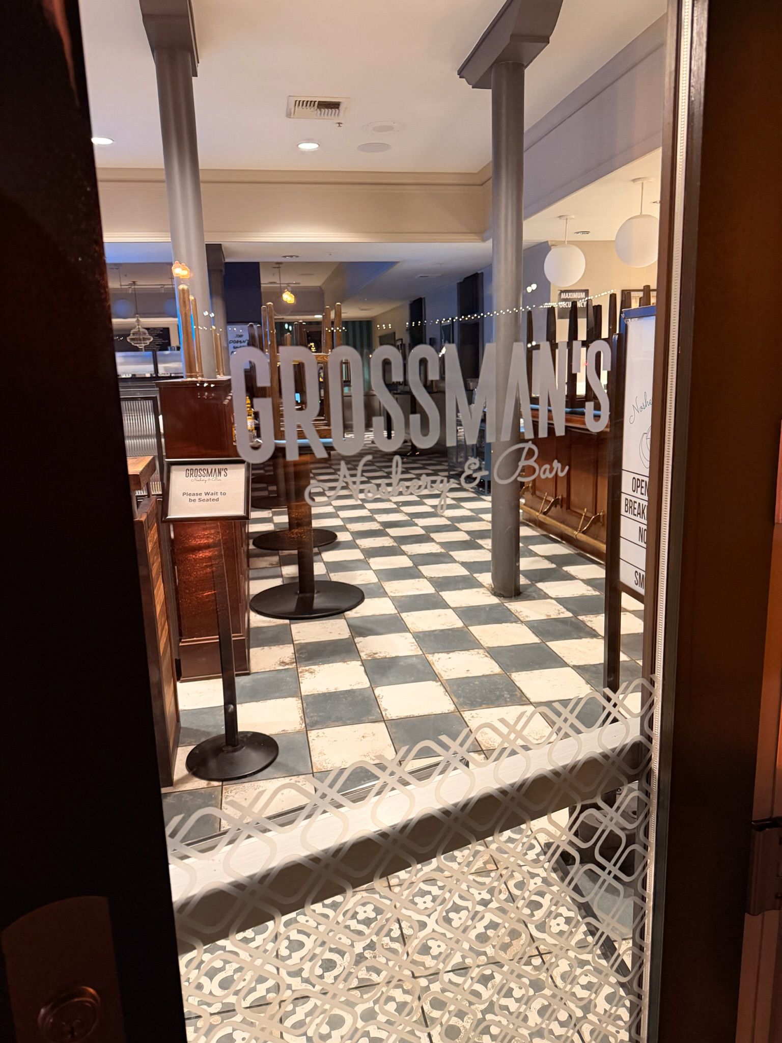Glass door entrance to Grossman's restaurant, with checkerboard floor and interior seating.