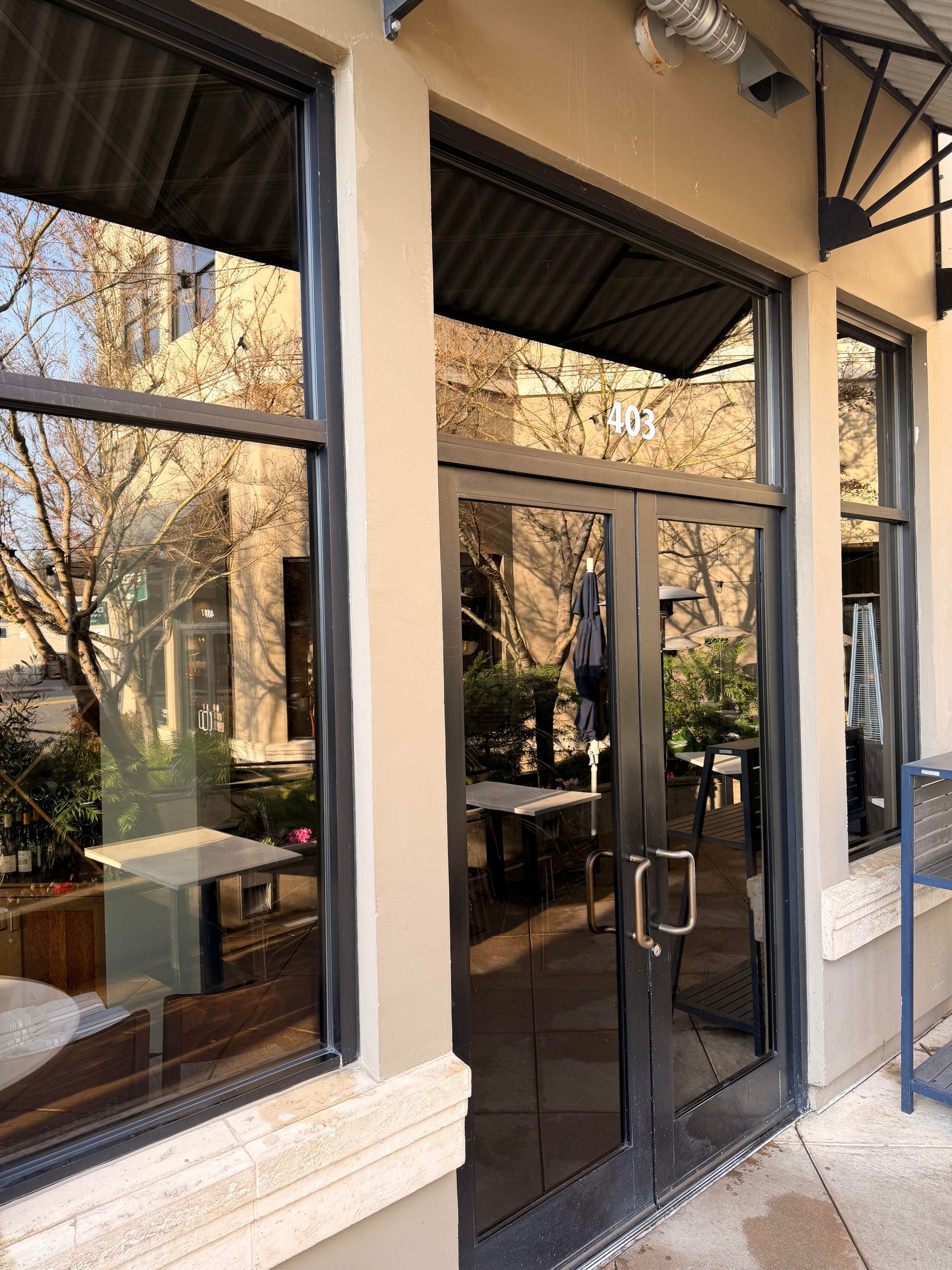 Exterior of a restaurant with glass doors and windows reflecting outdoor seating.