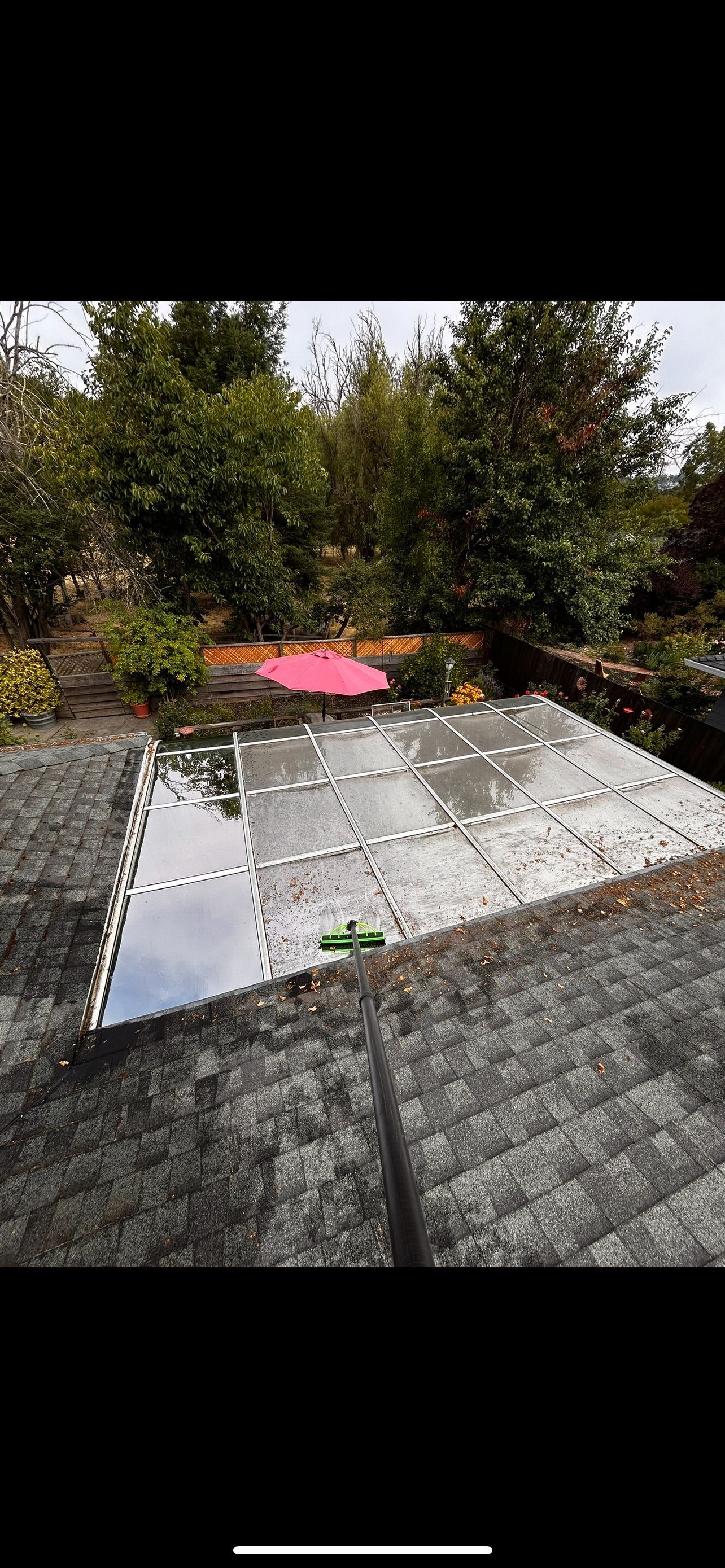 Solar panels on a roof, with trees in the background, a pink object in the middle.