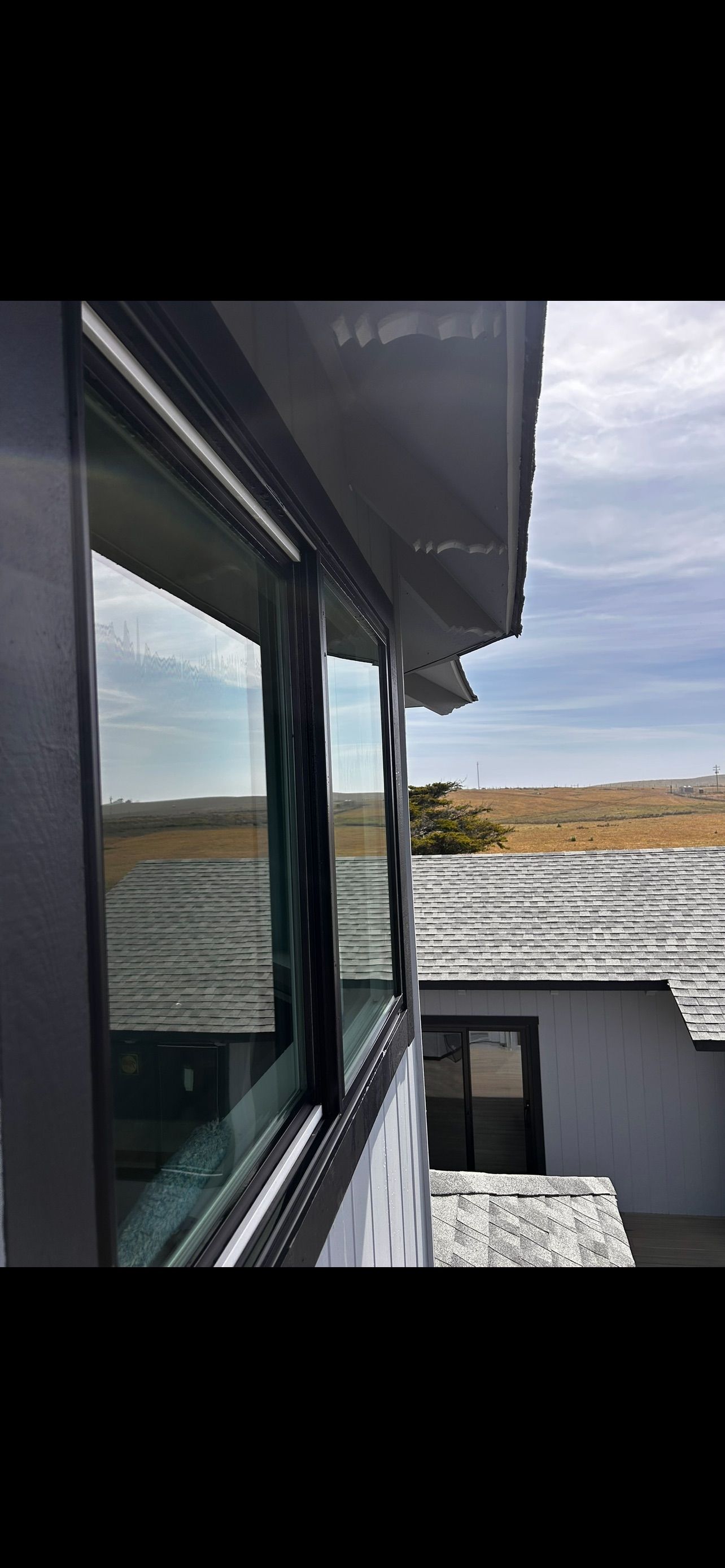View of windows and a roof against a landscape with a sky.