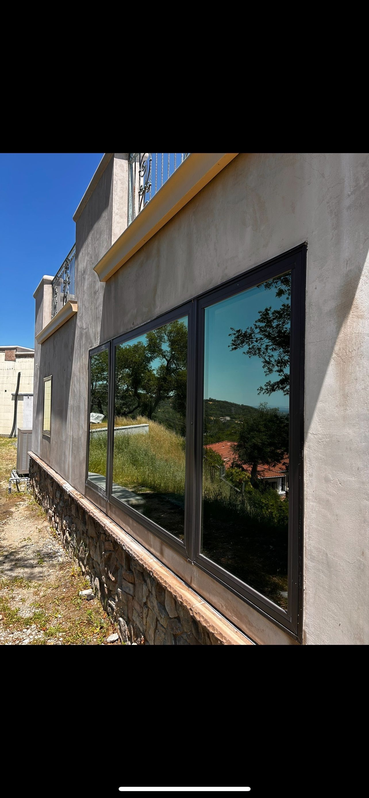 Exterior view of building with large windows reflecting trees and sky.