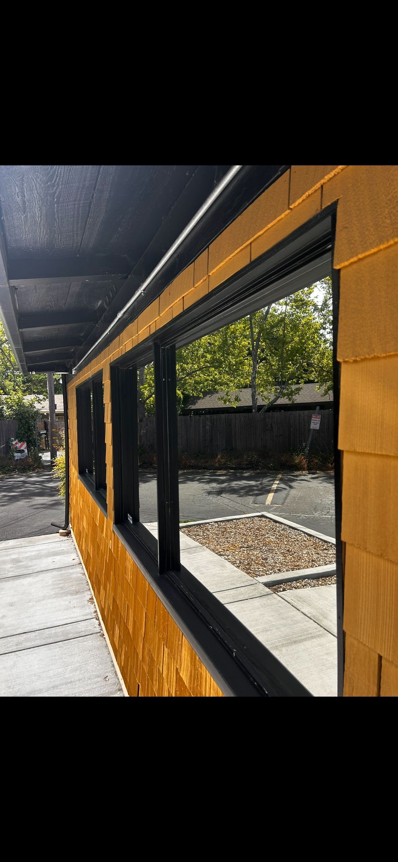 Exterior of a building with multiple windows. The building has wood siding and a black roof. 