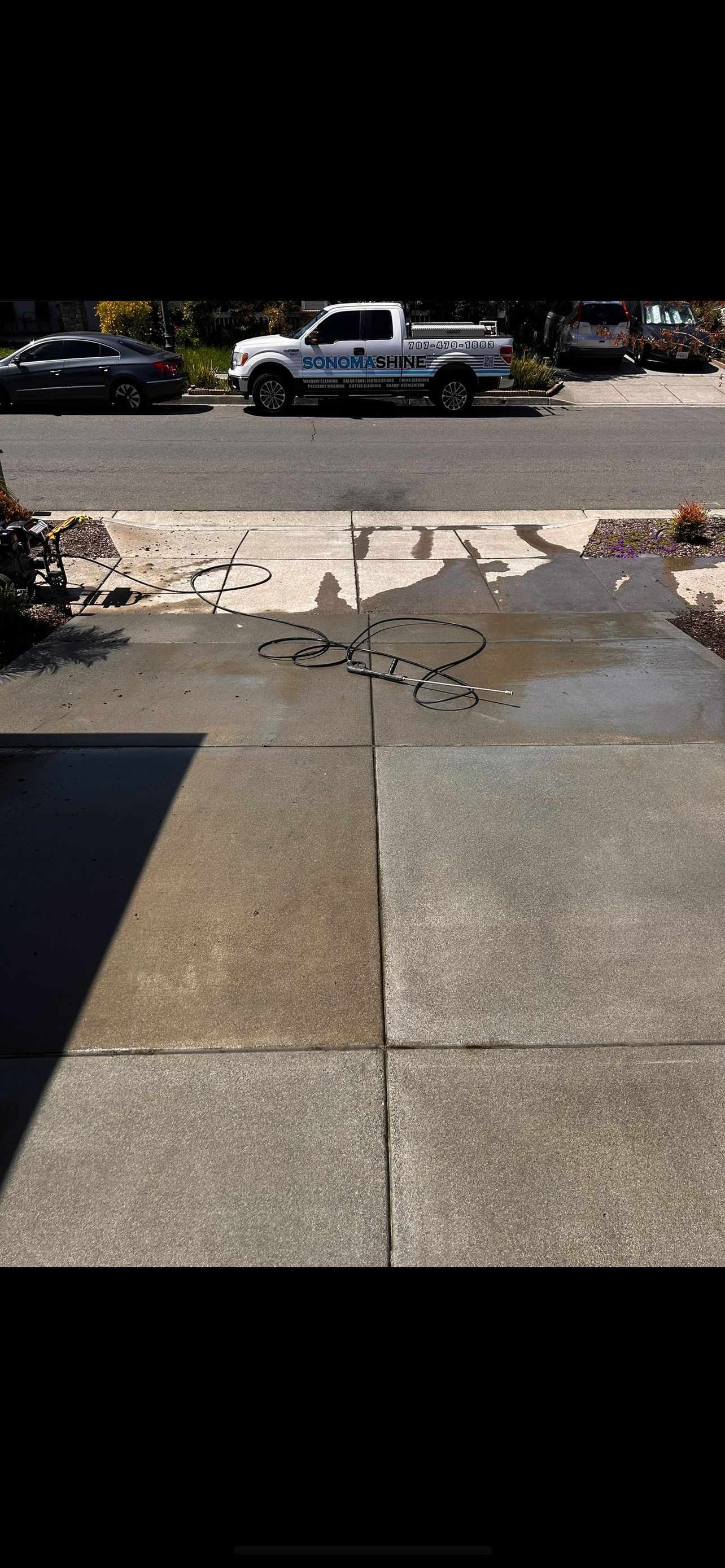 Sidewalk with water stains and a white pickup truck parked on the street.