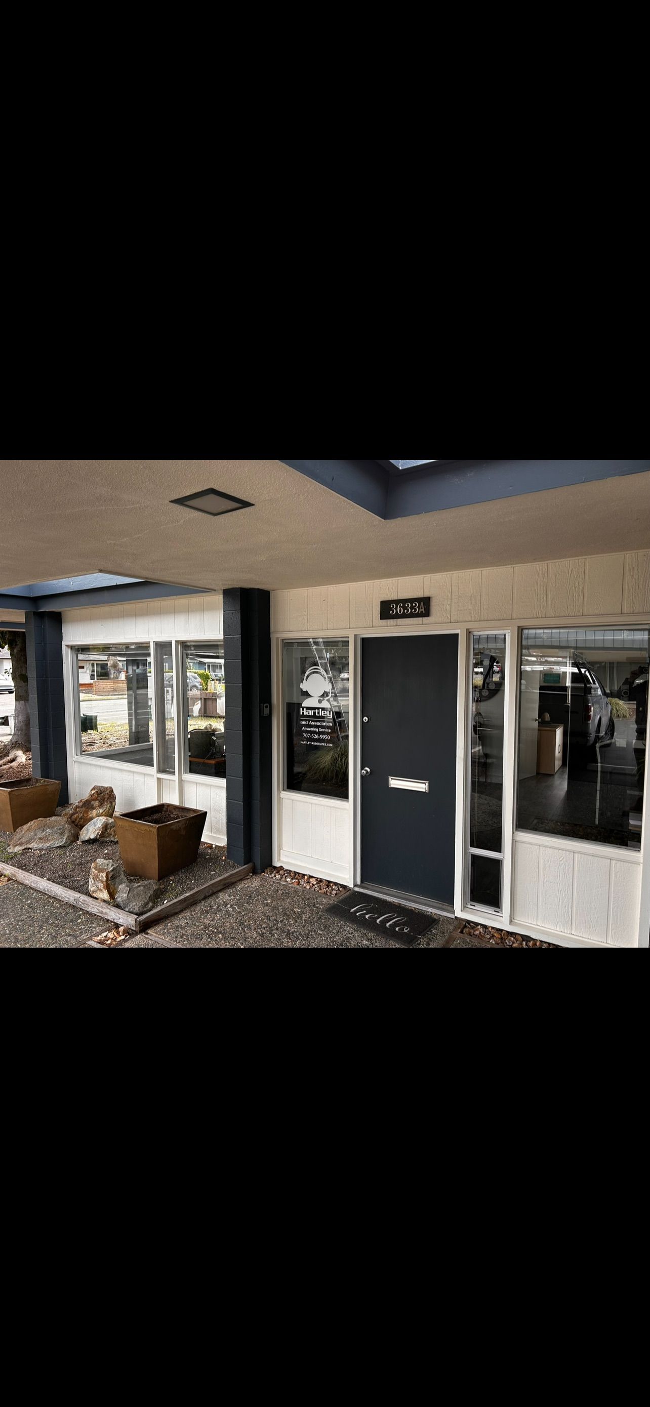 Exterior of a business with a blue door, glass windows, and a stone pathway.