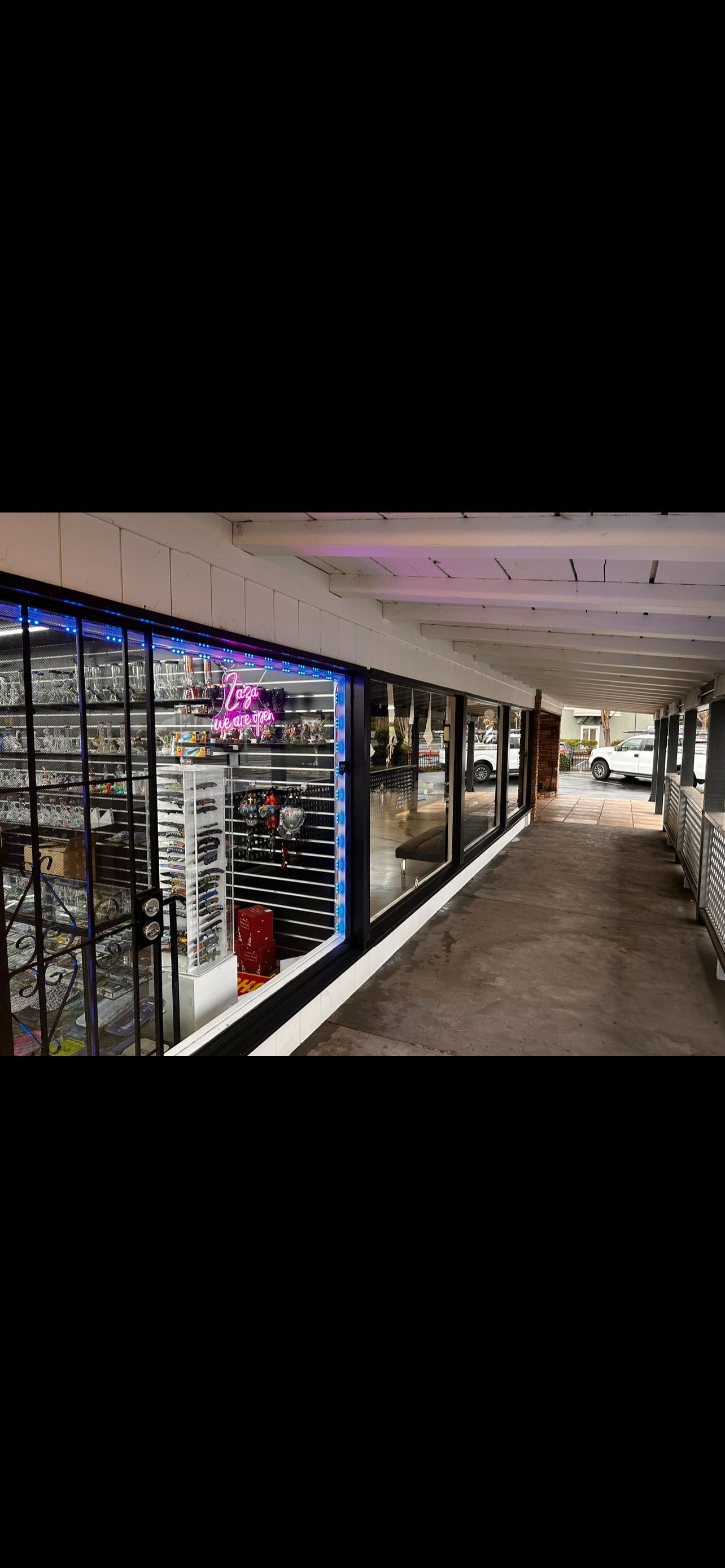 Shops in a hallway, one with a neon sign and eyewear in the window.