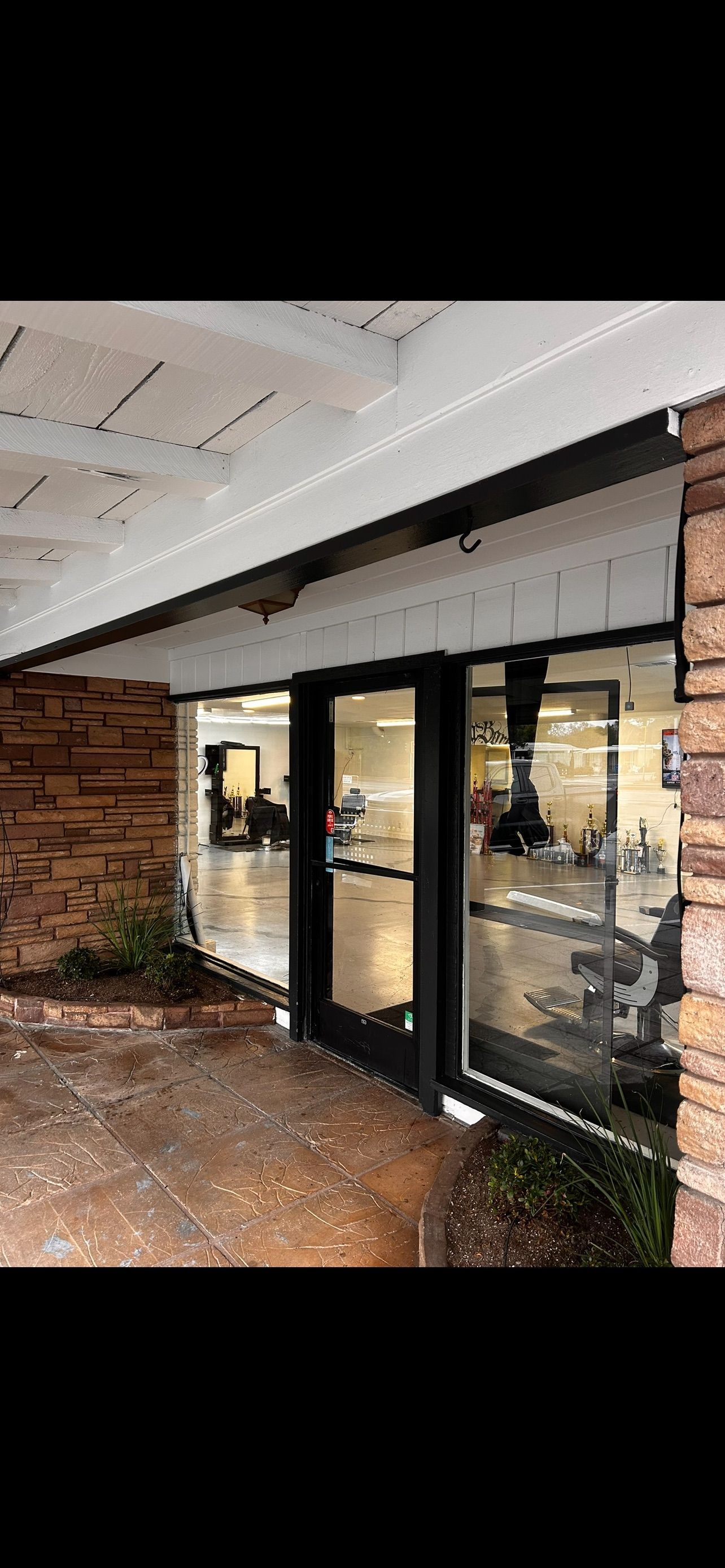 Entrance to a building with glass doors and a brick exterior, reflecting the interior.