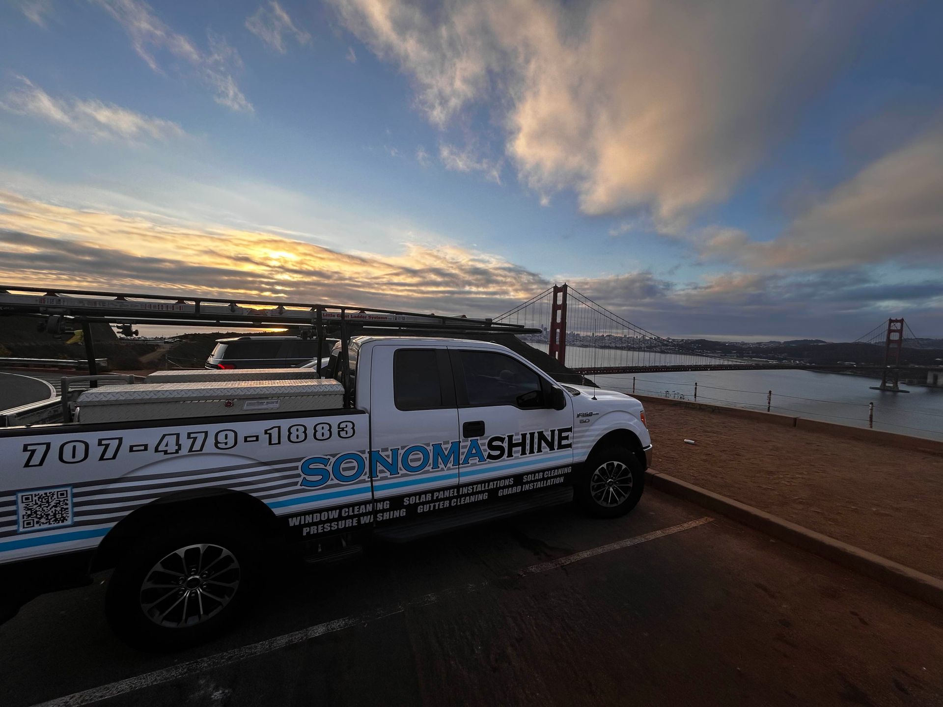White Sonoma Shine truck parked with Golden Gate Bridge in background at sunset.
