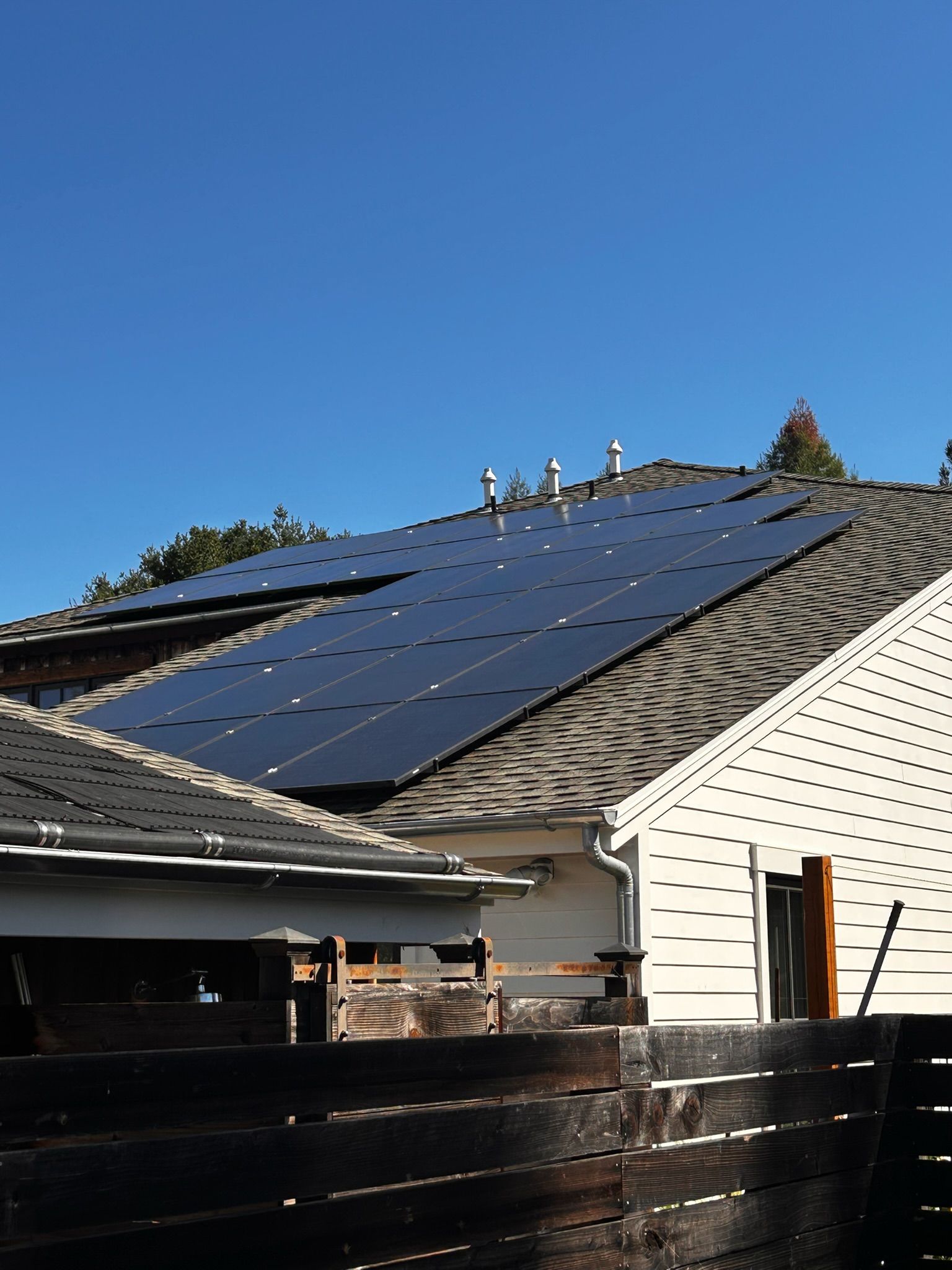 Solar panels on a residential roof against a clear, blue sky.