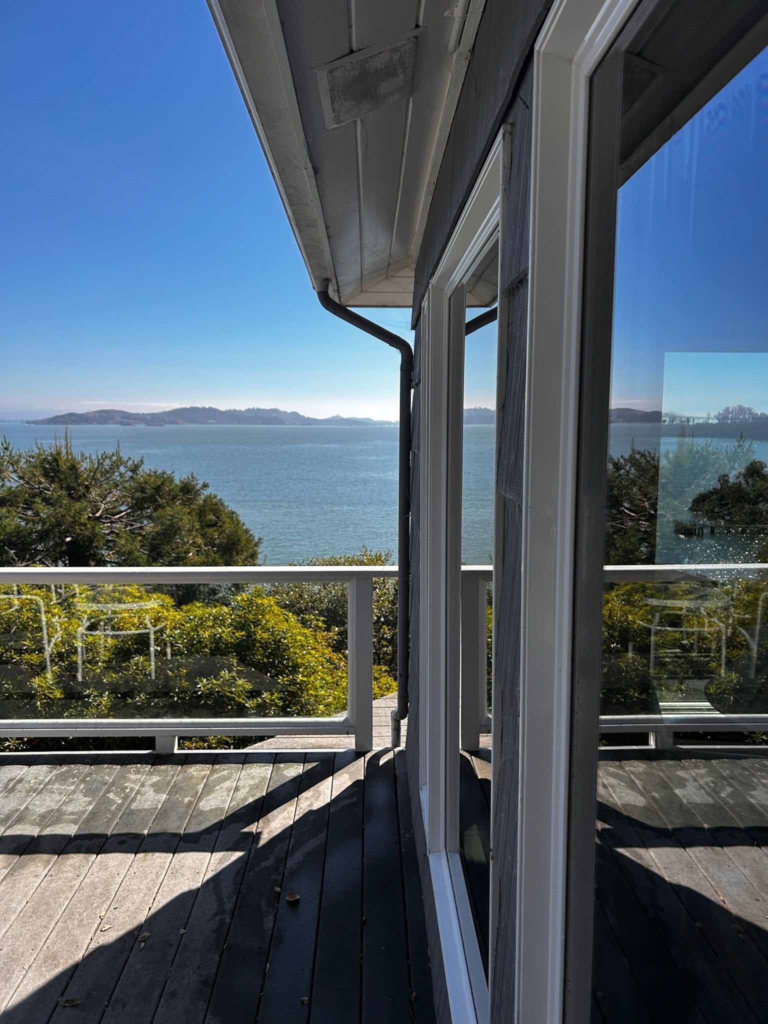 Deck overlooking a calm bay with mountains in the distance and a clear blue sky.