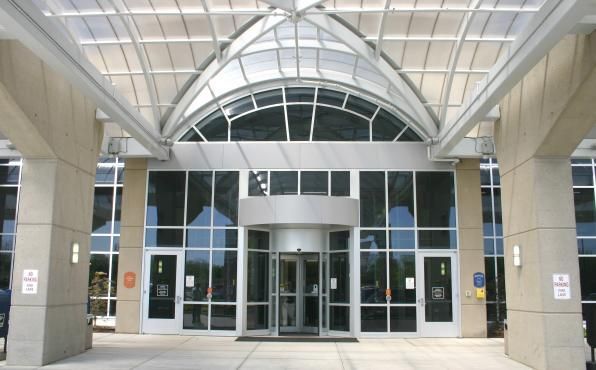 Modern building entrance with glass doors, arched canopy, and tall stone columns