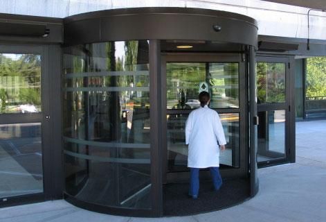 Glass double doors with white frames and handle, reflecting a cityscape and open blue sky.