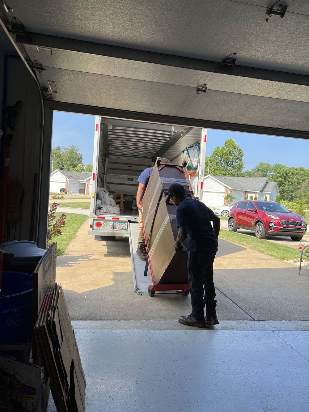 A man is loading a couch into a truck in a garage.