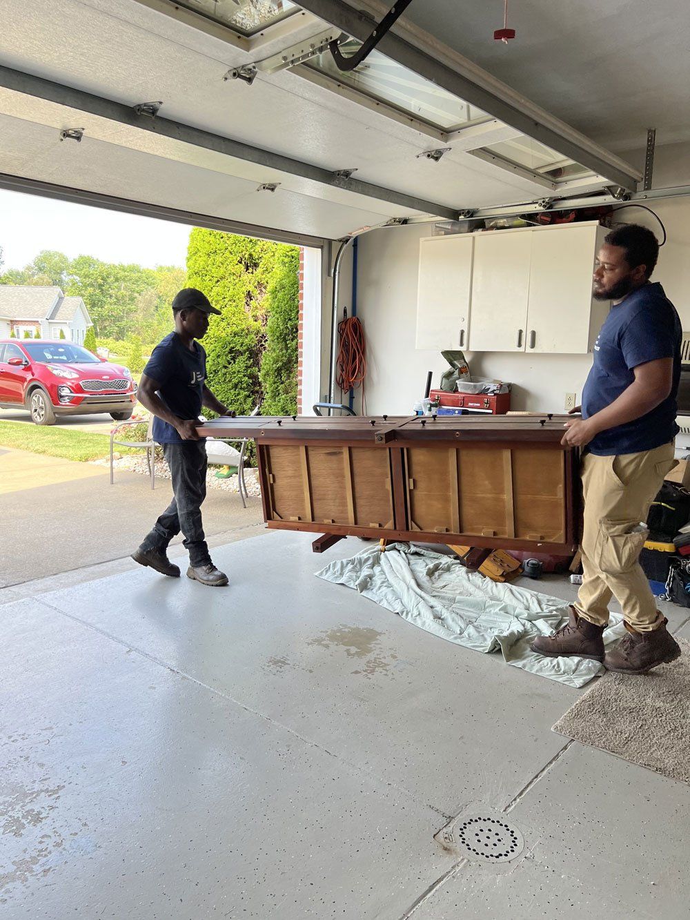Two men are carrying a pool table into a garage.