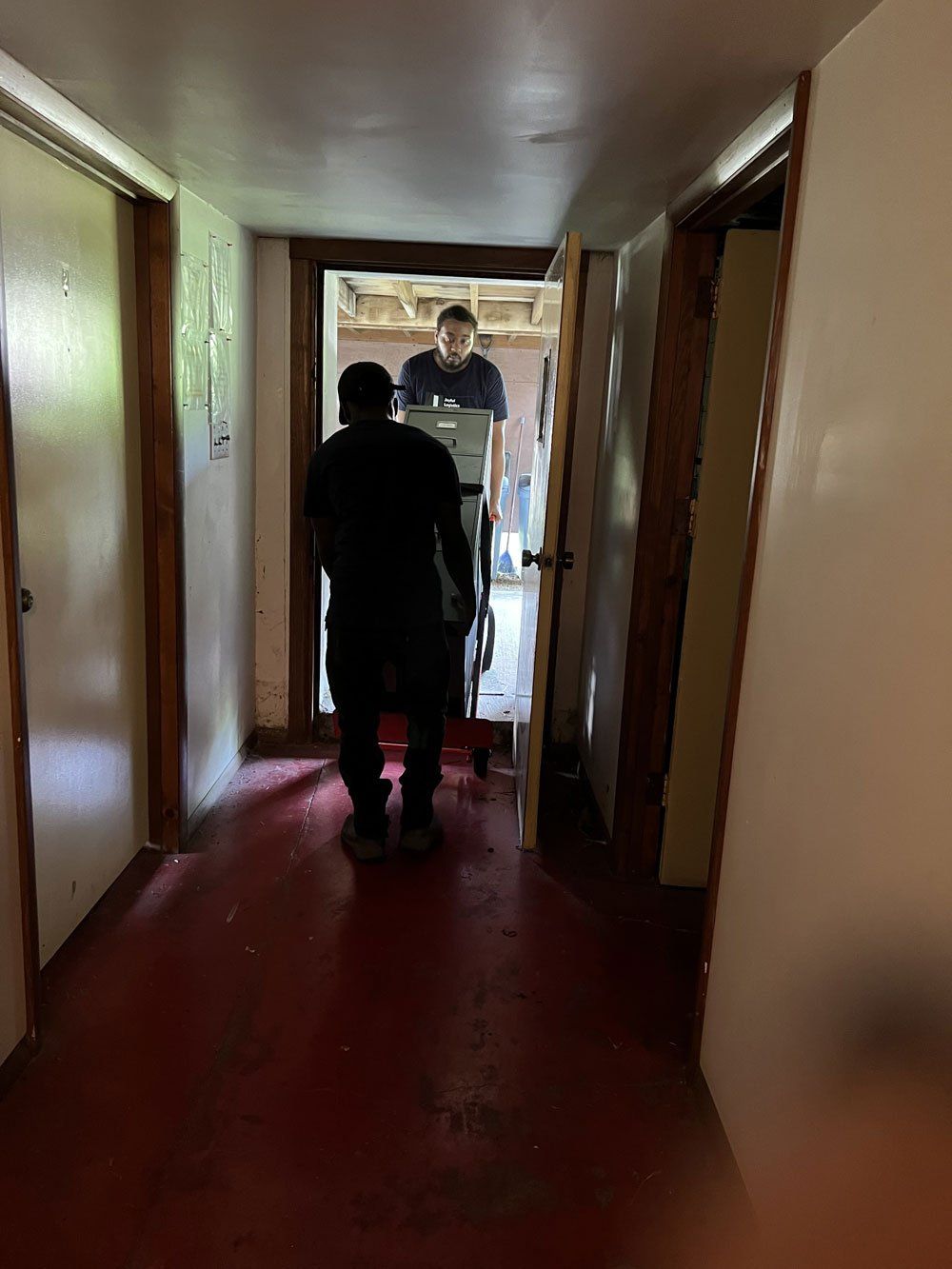 A man is pushing a box down a hallway.