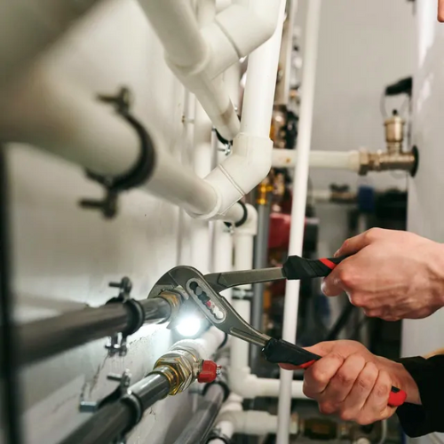 A person is working on a pipe with a wrench.